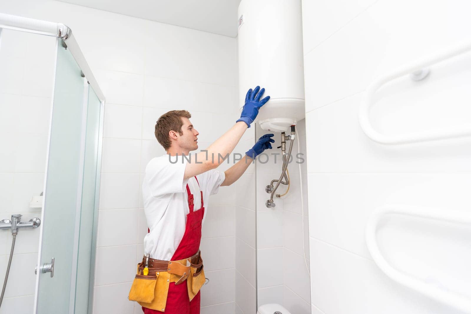 Professional plumber checking a boiler and pipes, boiler service concept. by Andelov13