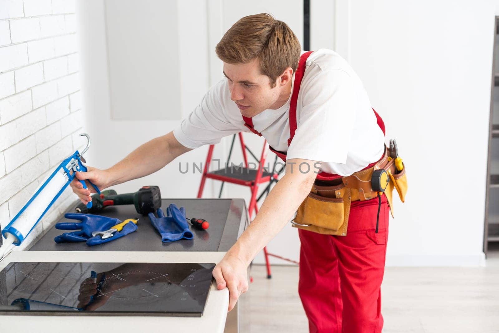 craftsman installs hob in kitchen. Household Appliance Installation Services Concept.