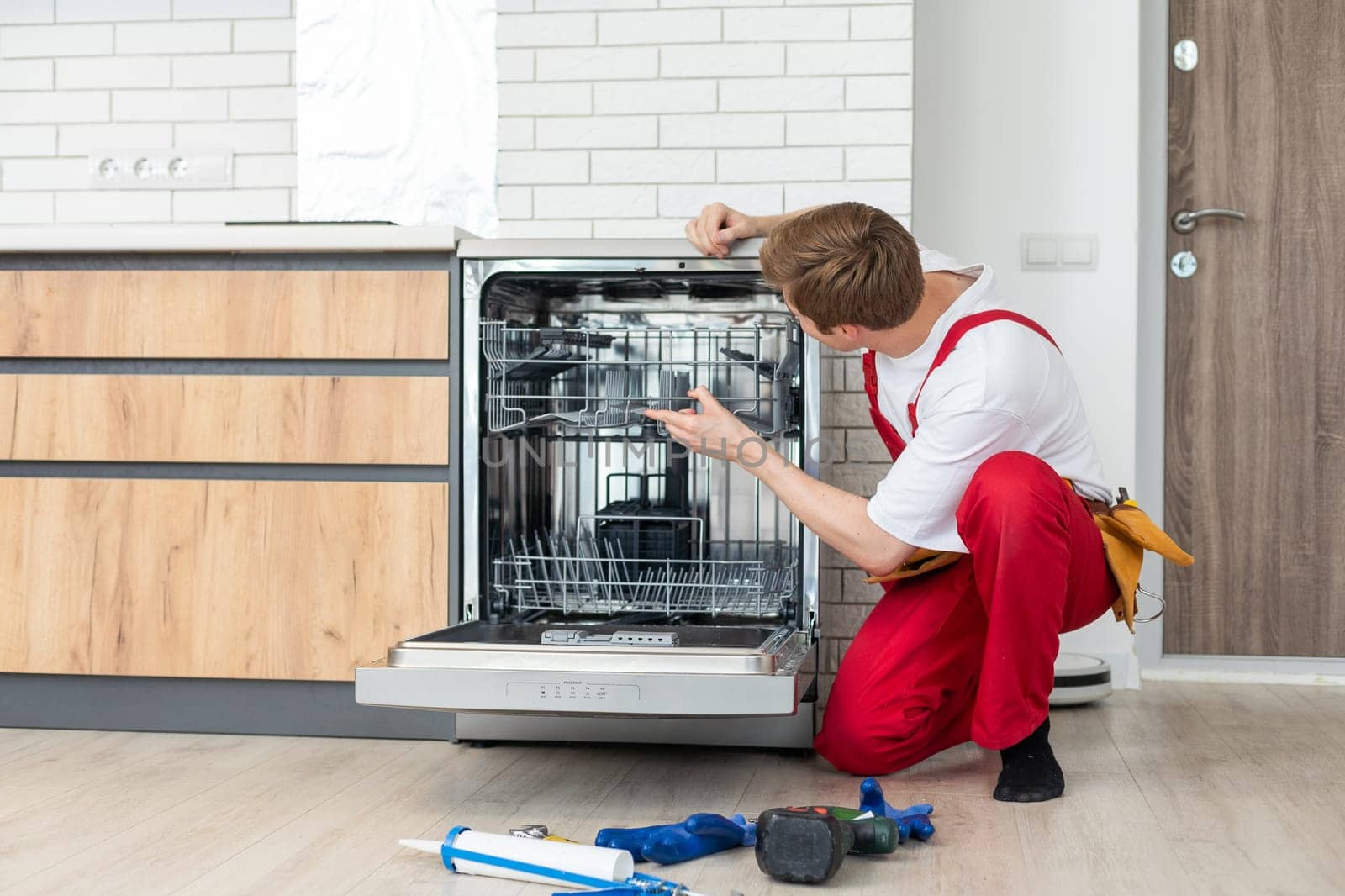 Concept maintenance service of home appliances. Worker cleans filter in the dishwasher. Male repairman checking food residue filters.