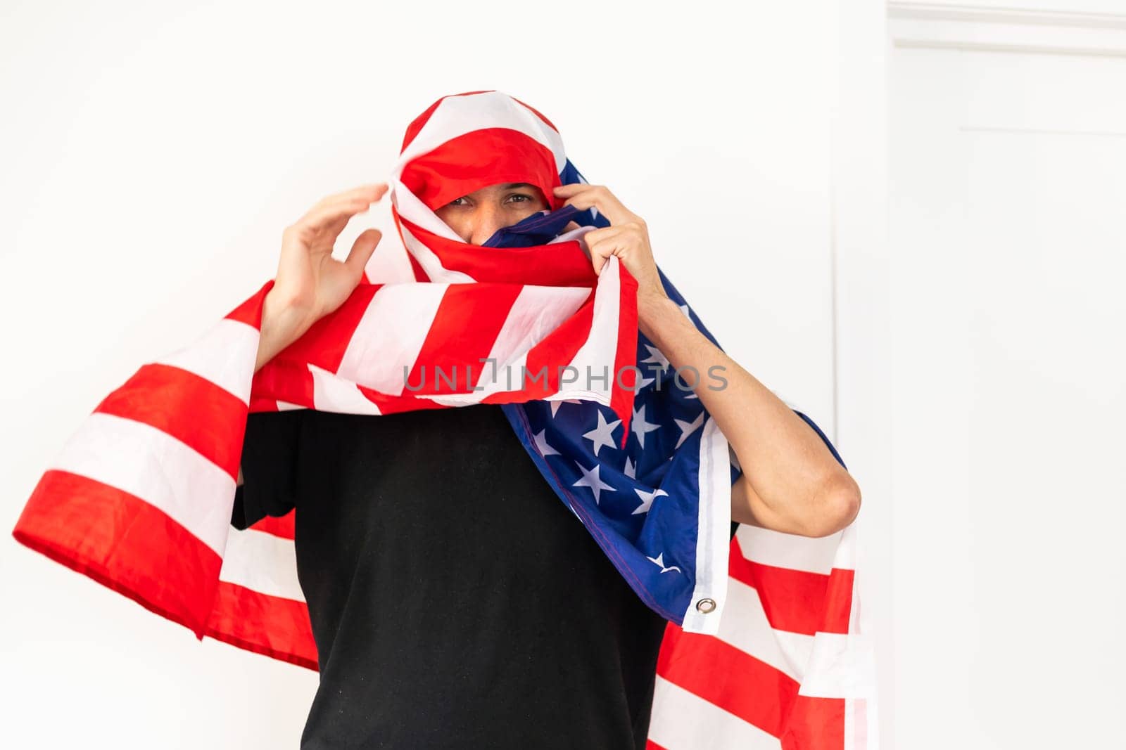 Very emotional American patriot young man with painted face covered by National Flag of United States of America celebrating Independence Day on 4th of July by Andelov13