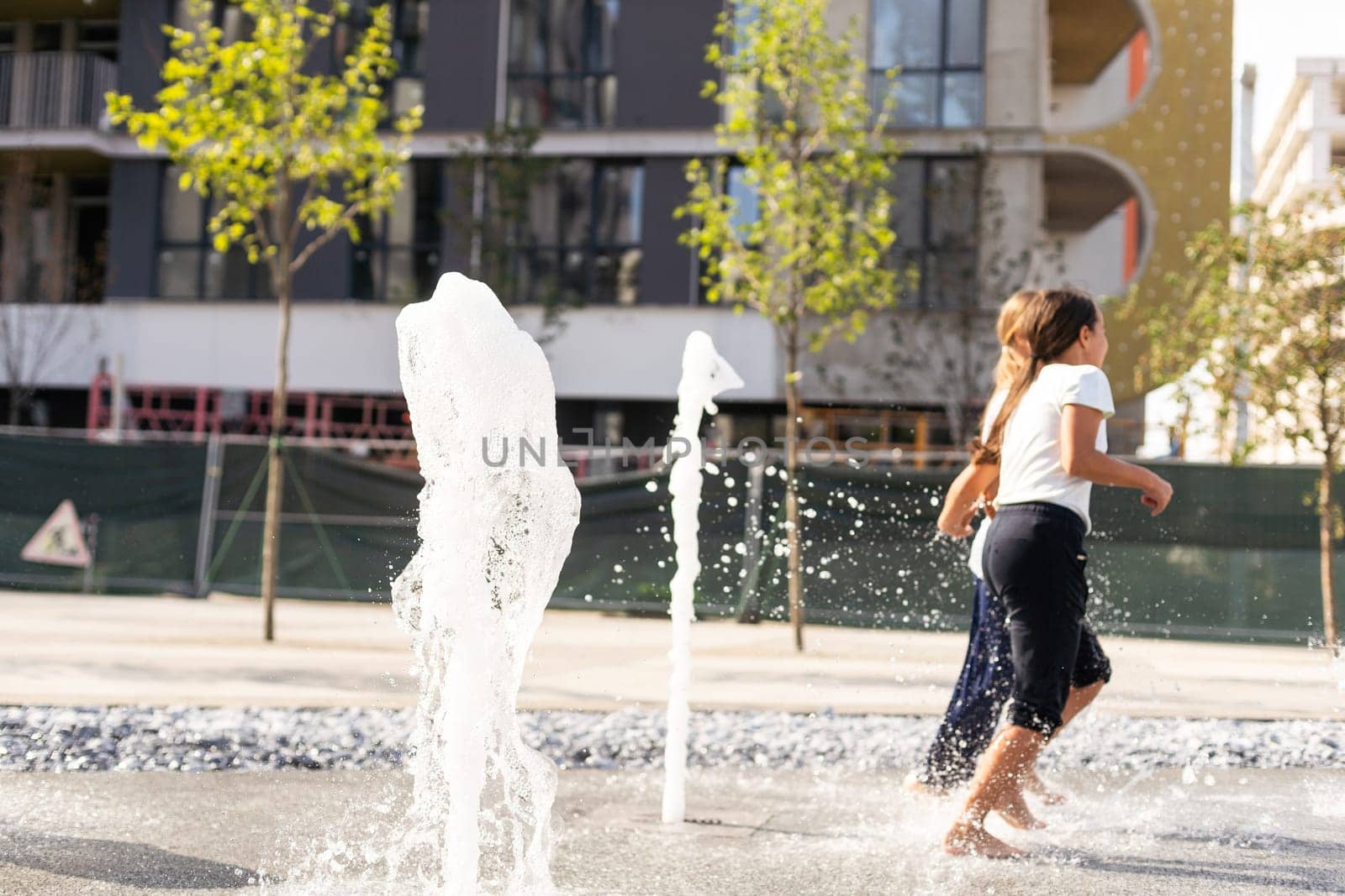 life of children in a modern city - little girl having fun with fountains. High quality photo