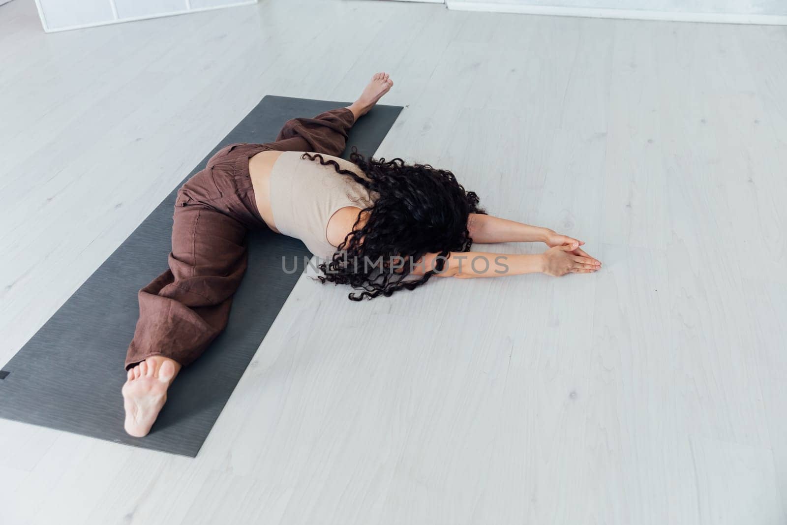 Beautiful sporty curly woman doing yoga asana fitness exercises on the floor by Simakov