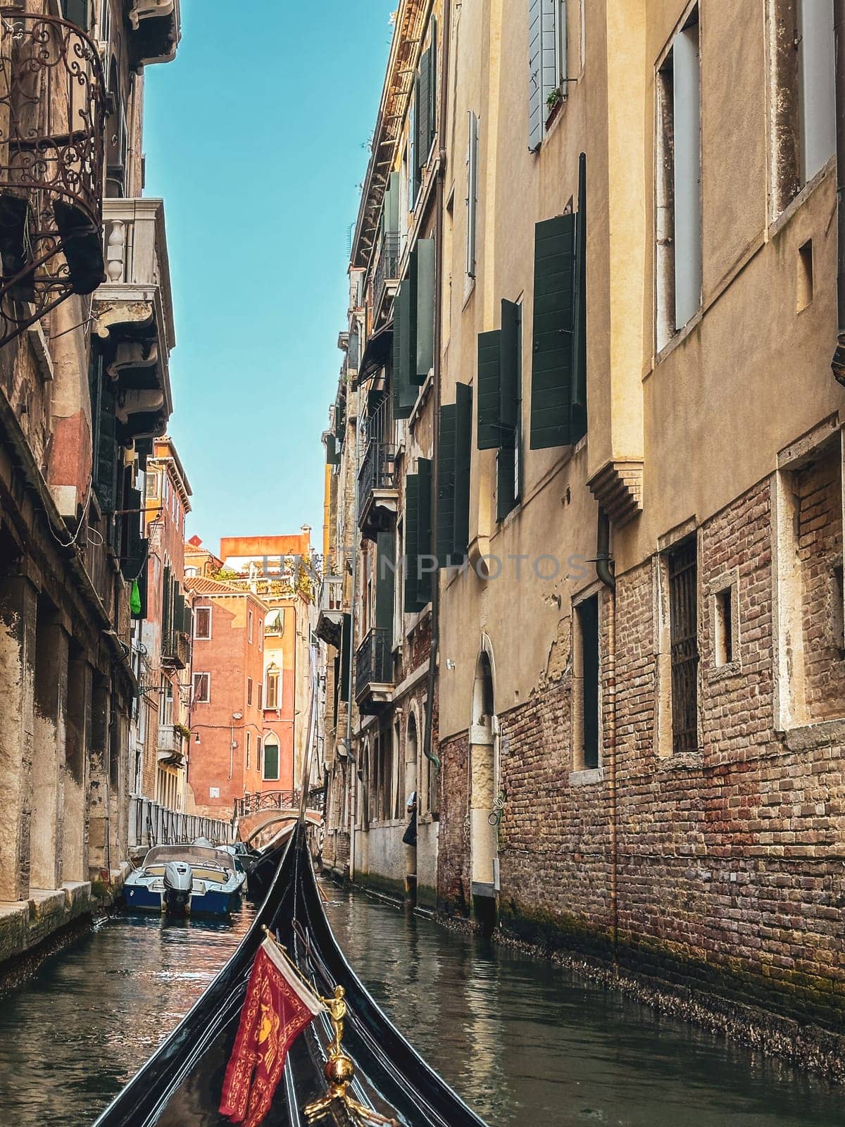 Gondola moving between houses in narrow canals within the city of Venice, Italy by Sonat