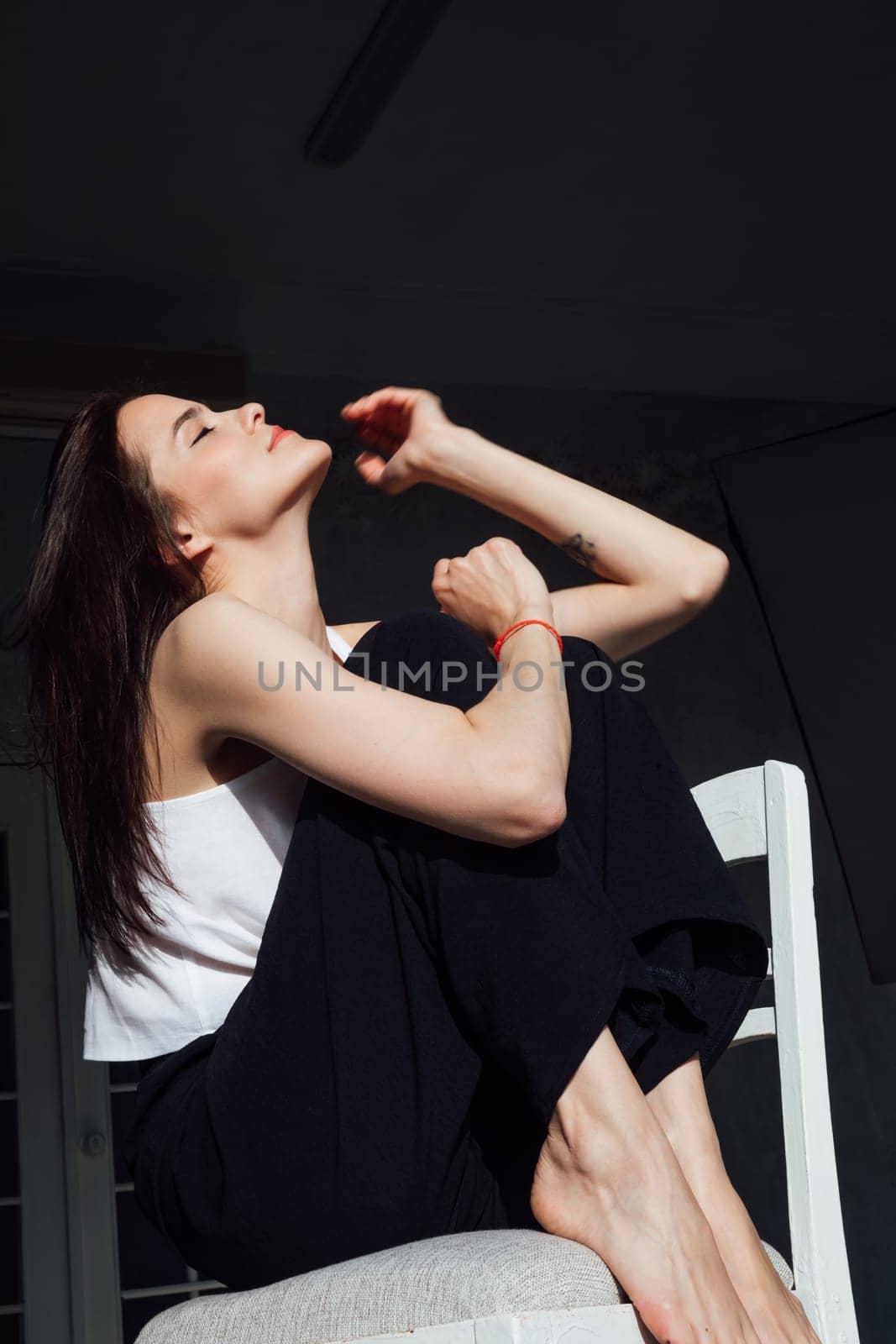 Portrait of a beautiful young slender woman sitting on a chair by Simakov