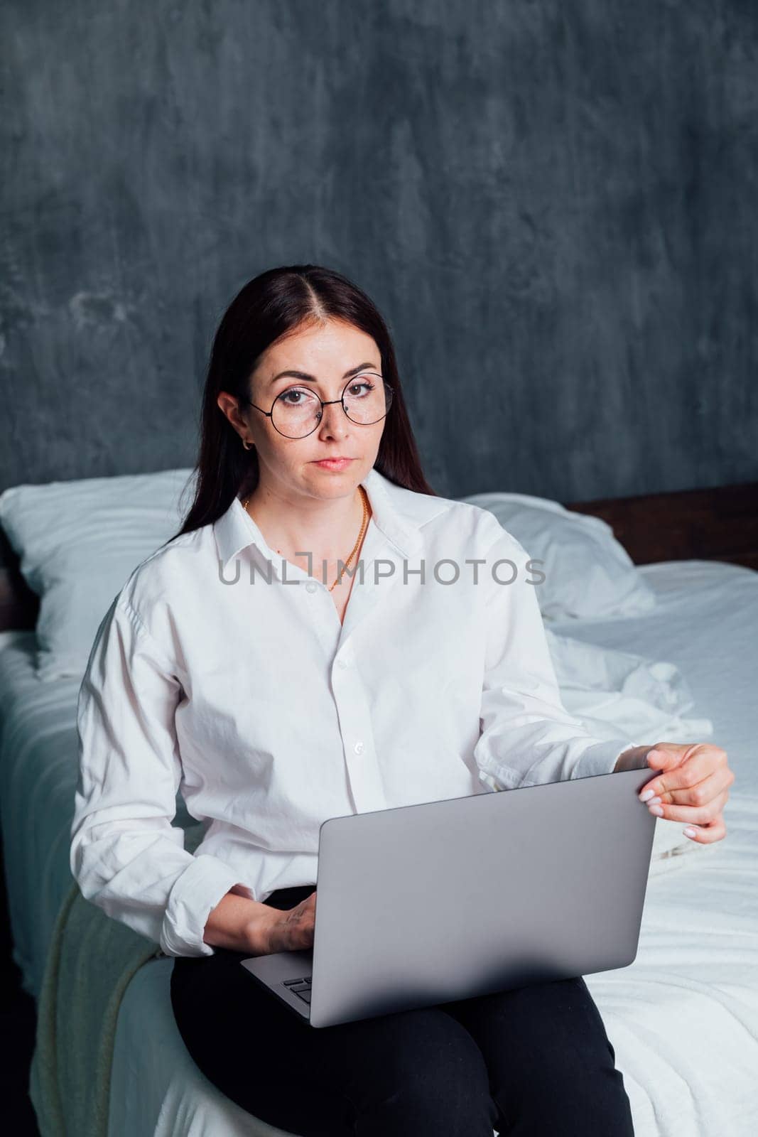 Business woman working at computer in bedroom on bed by Simakov