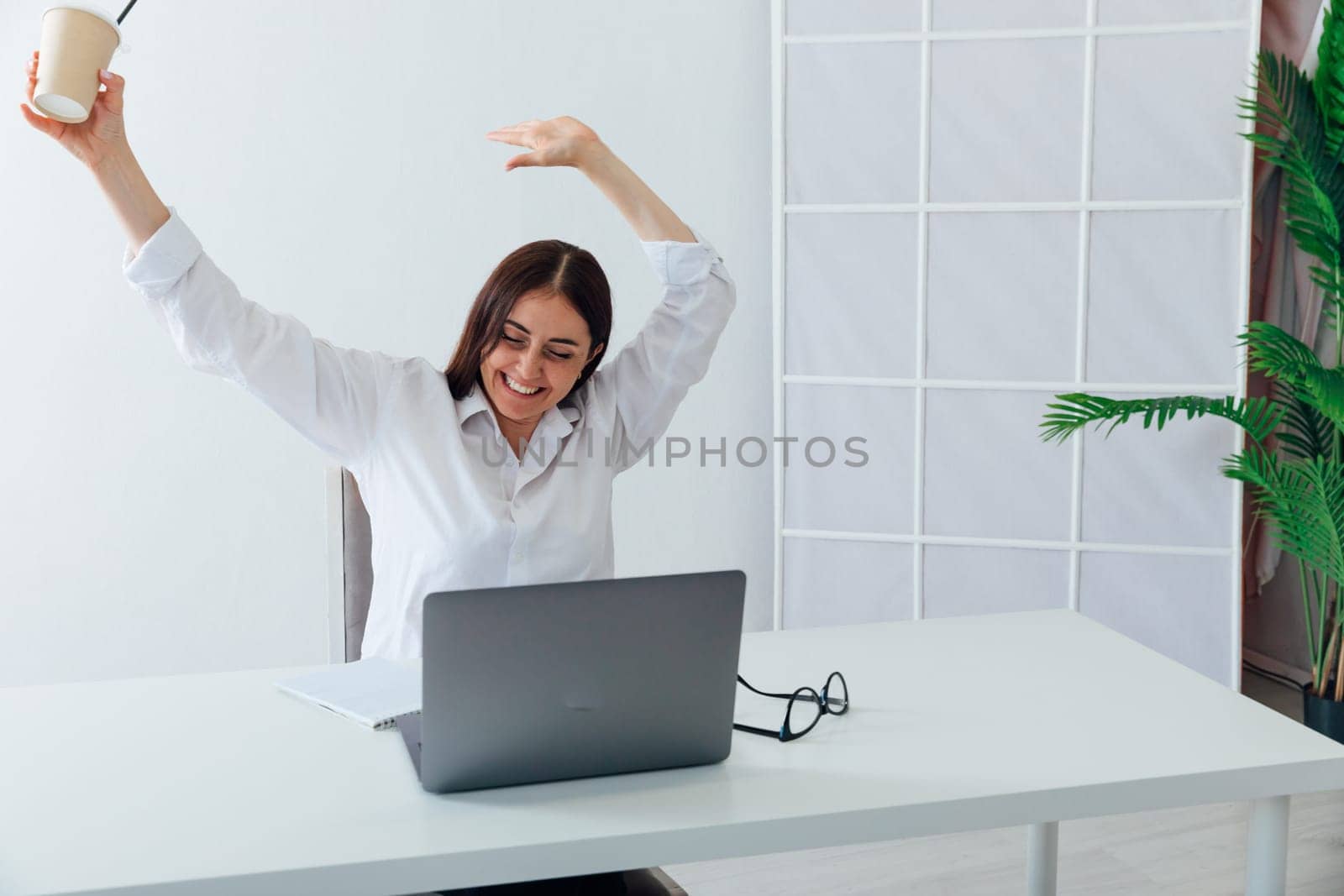 Business woman working online at computer showing joy with her hands by Simakov