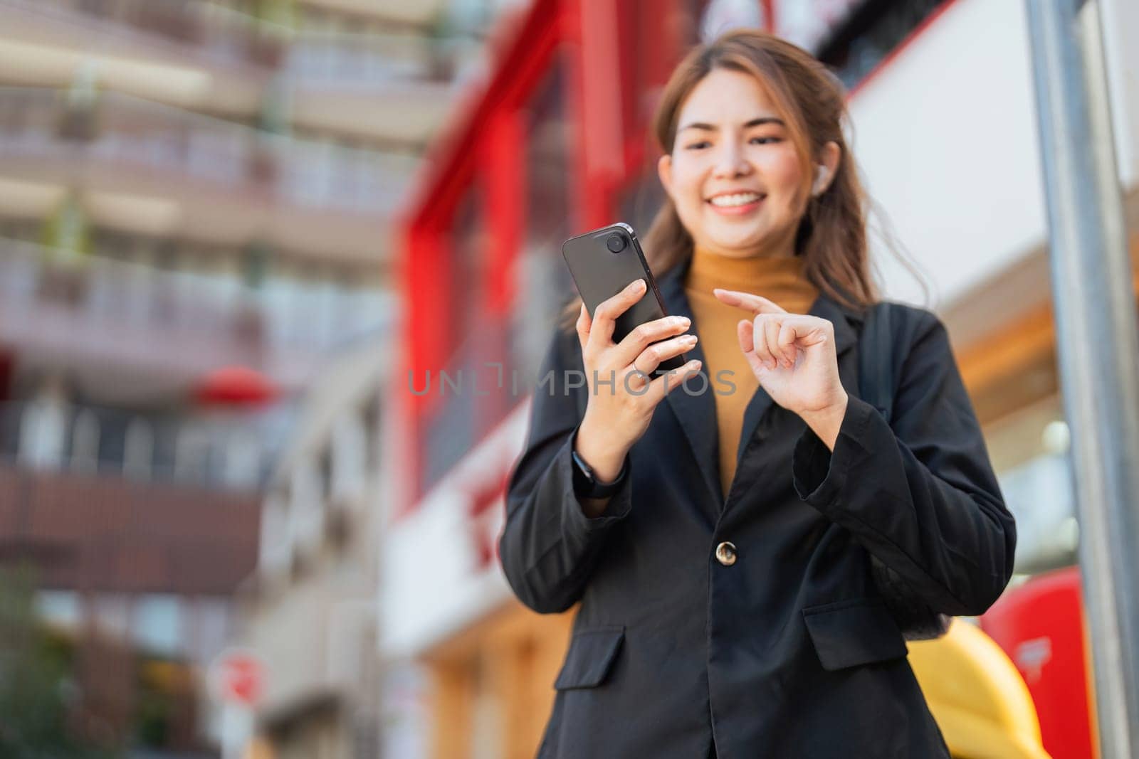 Business woman successful using smartphone walking outdoors to work. beautiful woman going to working with smartphone walking near office building by nateemee