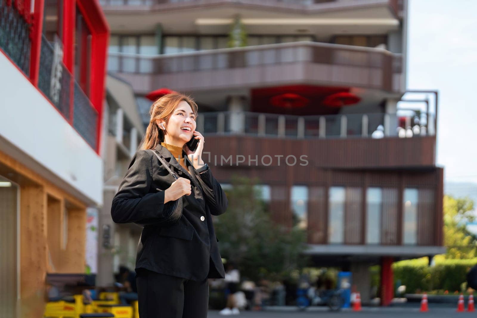 Business woman successful using smartphone walking outdoors to work. beautiful woman going to working with smartphone walking near office building by nateemee