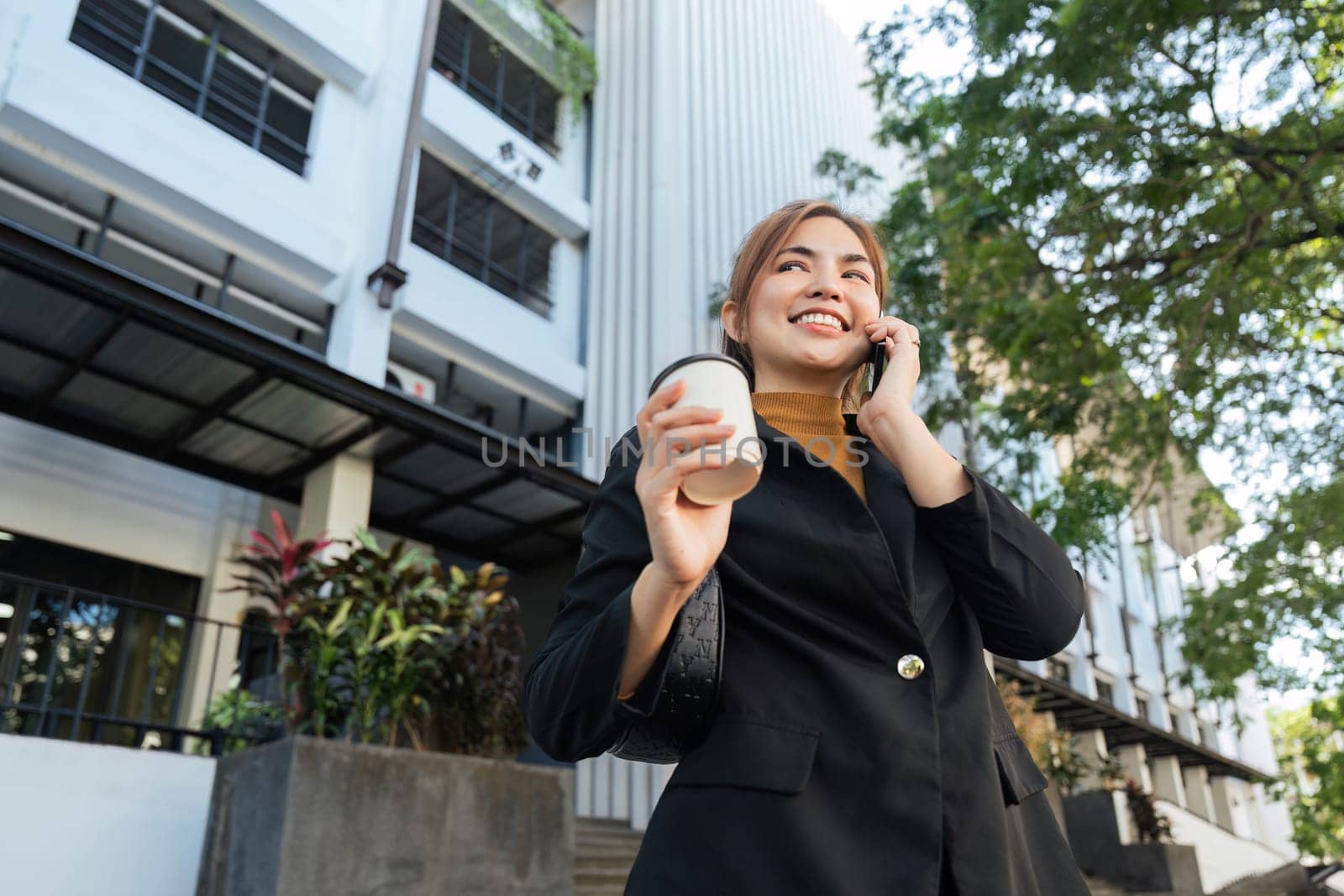 Beautiful young woman Using smartphone standing on the city street along with drinking coffee. portrait of gorgeous Smiling female using mobile phone by nateemee