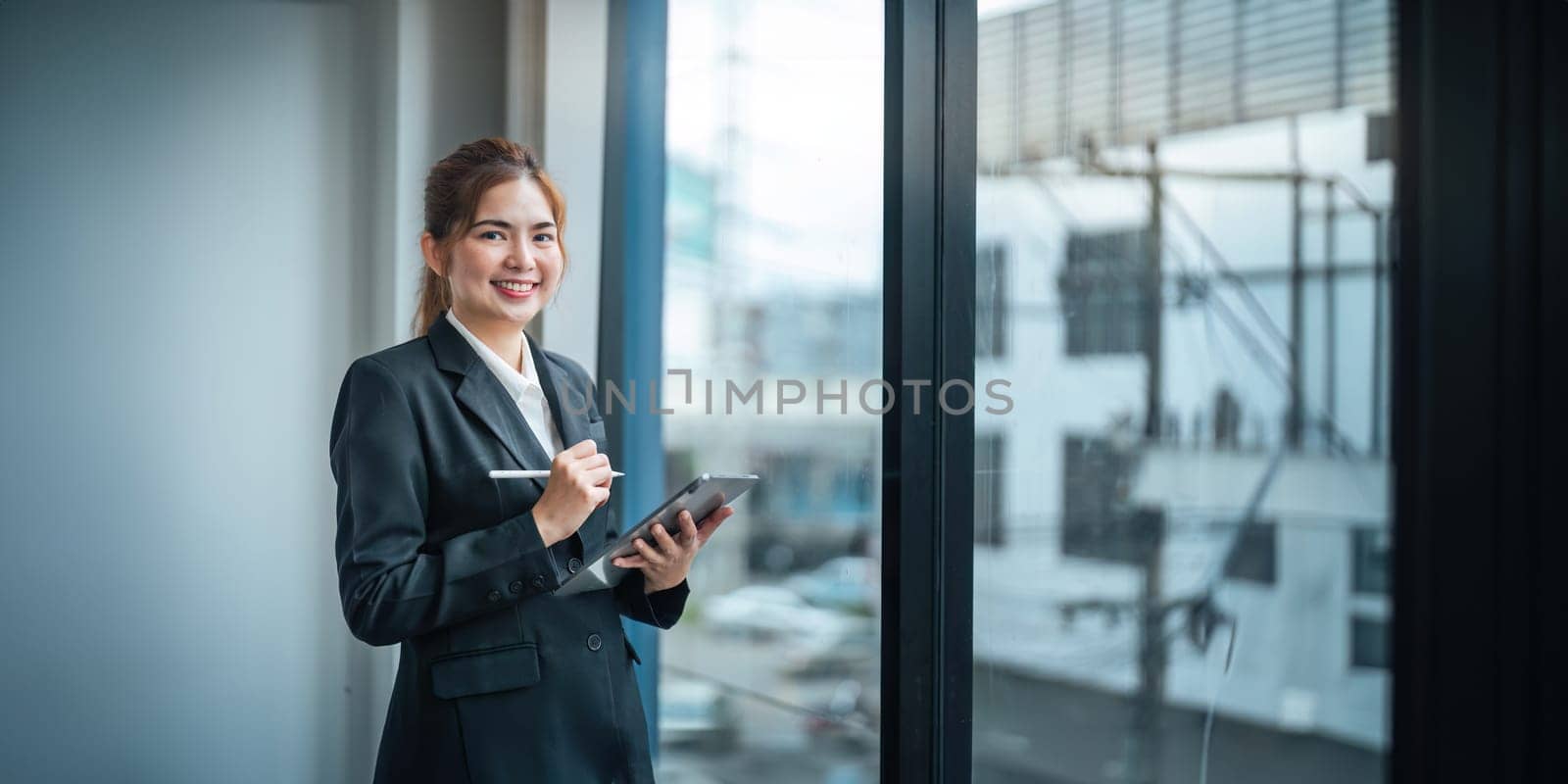 Young asian businesswoman looking out window in meeting room with confidence.
