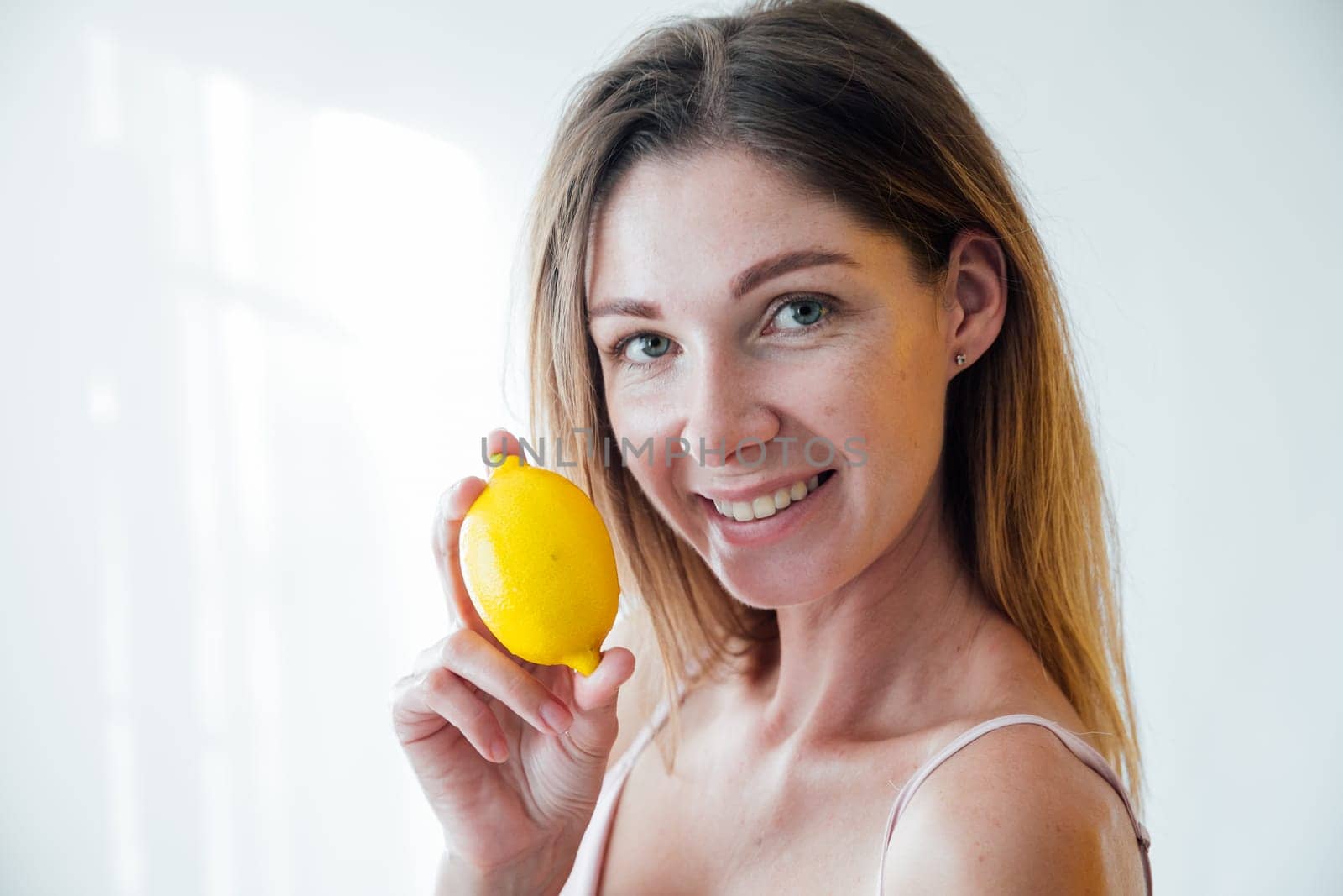 woman holding yellow lemons and smiling