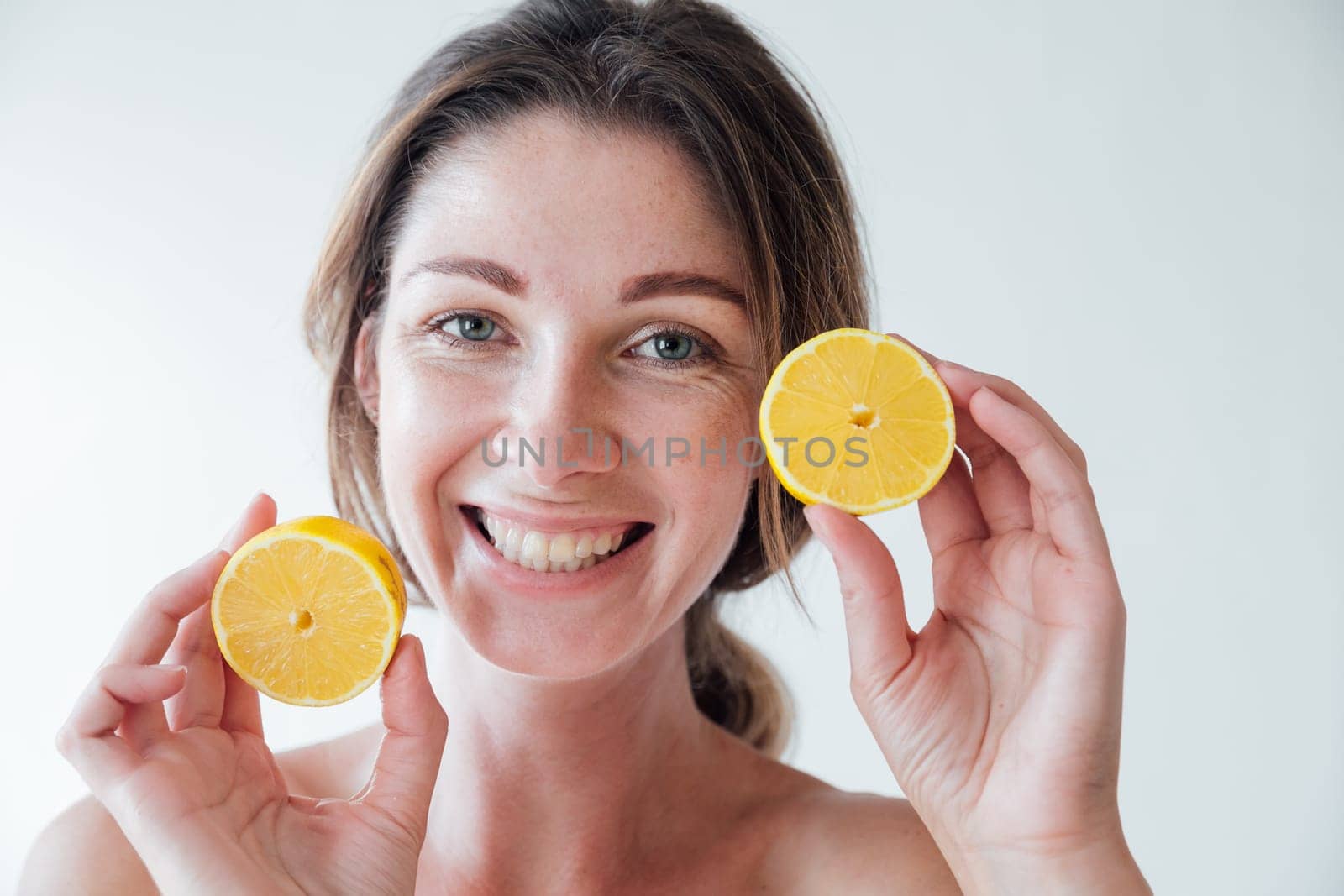 Beautiful woman holding yellow lemons and smiling by Simakov