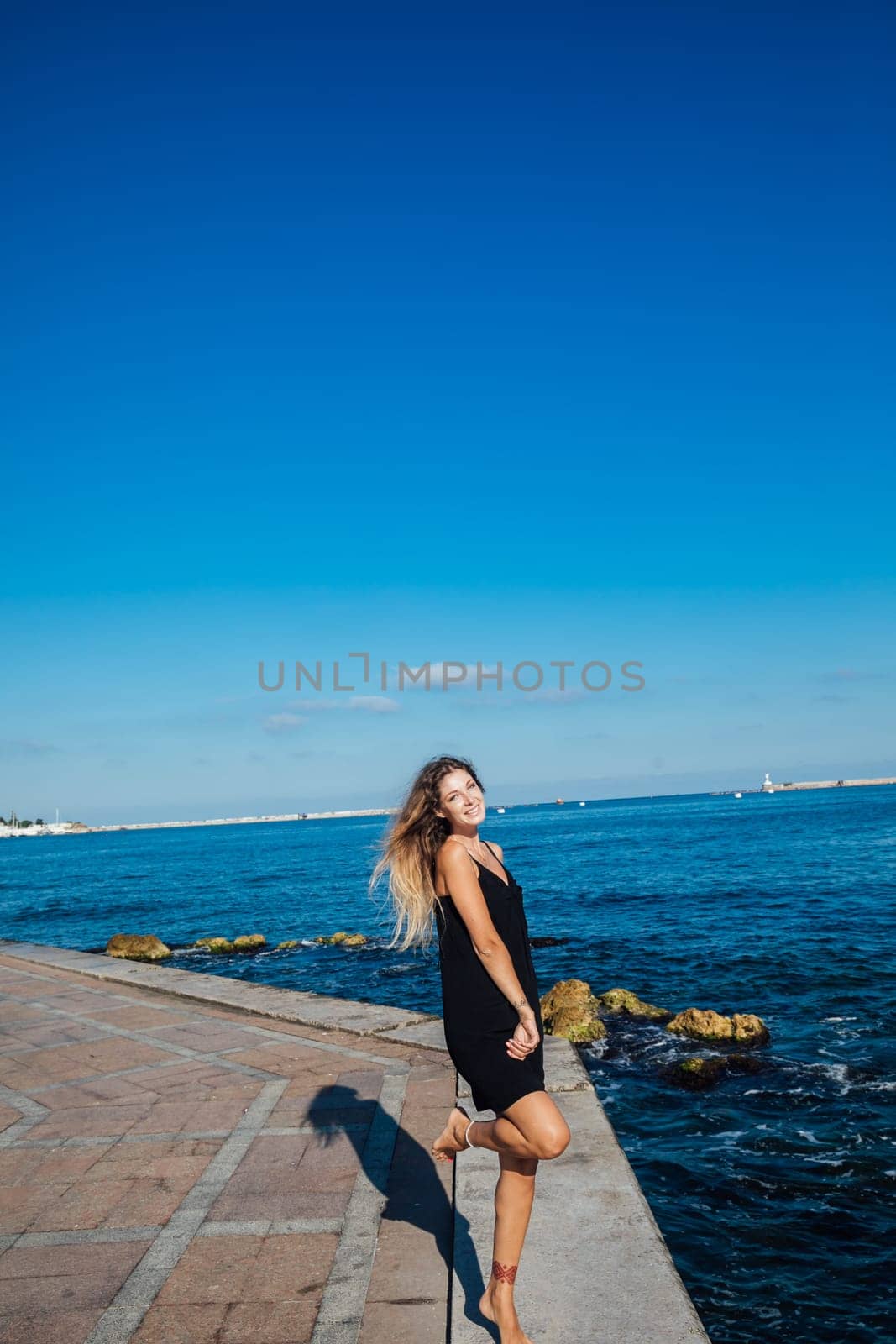 woman in black summer dress on a walk by the sea