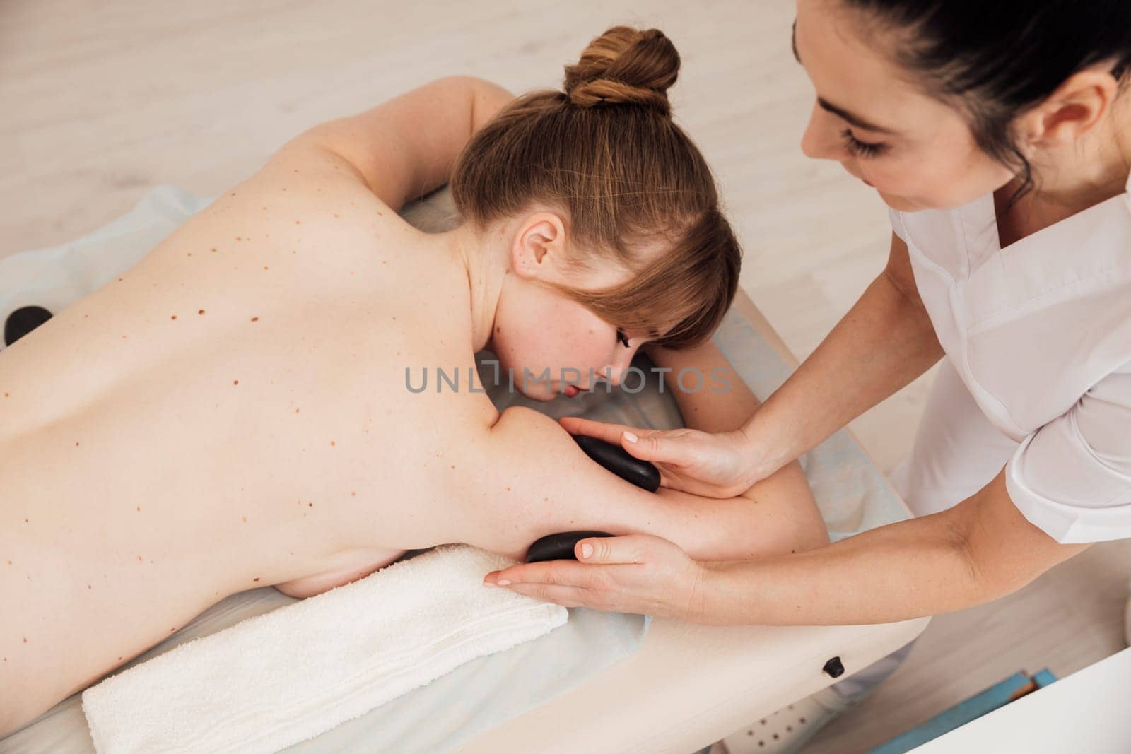 Female masseur doing therapeutic back massage in spa therapy by Simakov