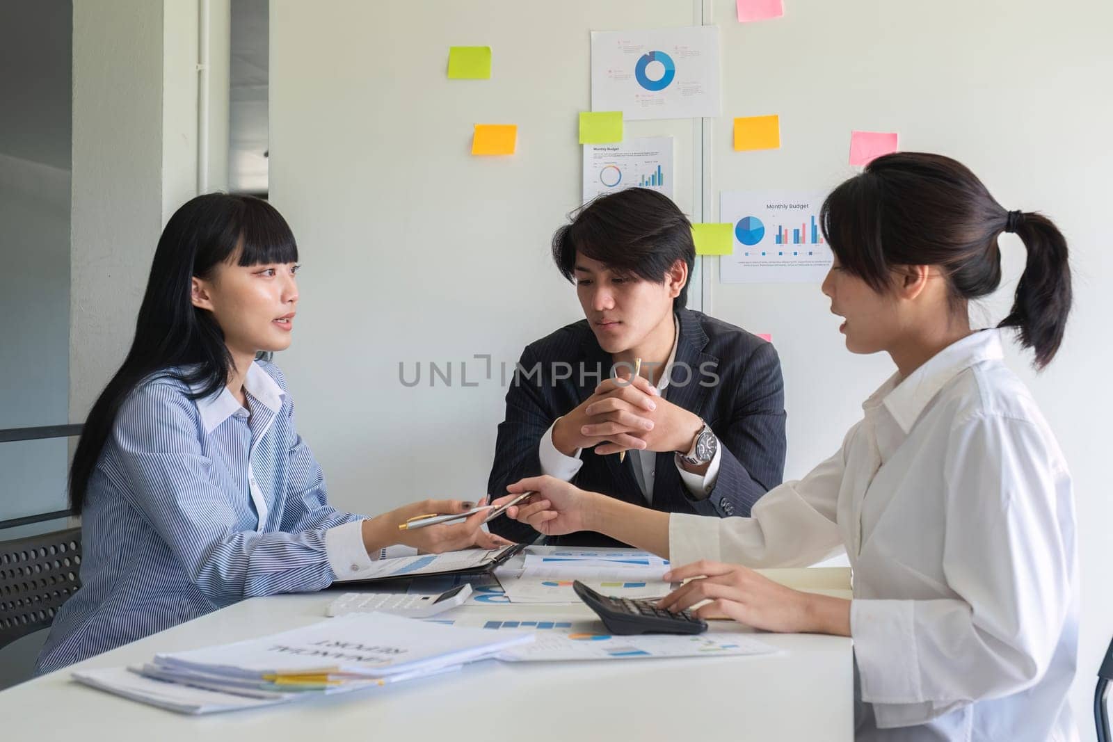 A professional business team is meeting to discuss company management practices in a modern conference room. by wichayada