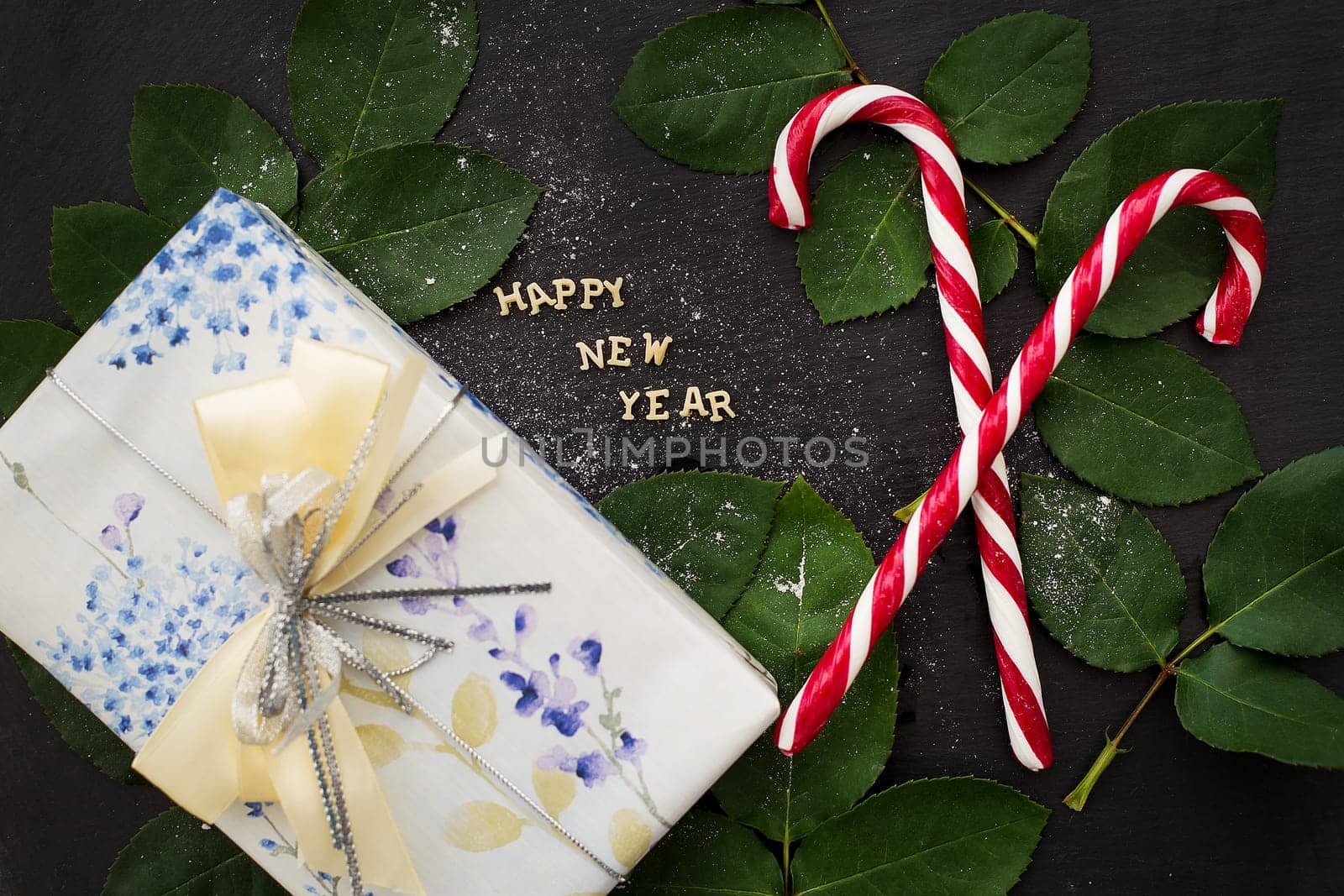 inscription of new year on a black board with a nice gift and red candy