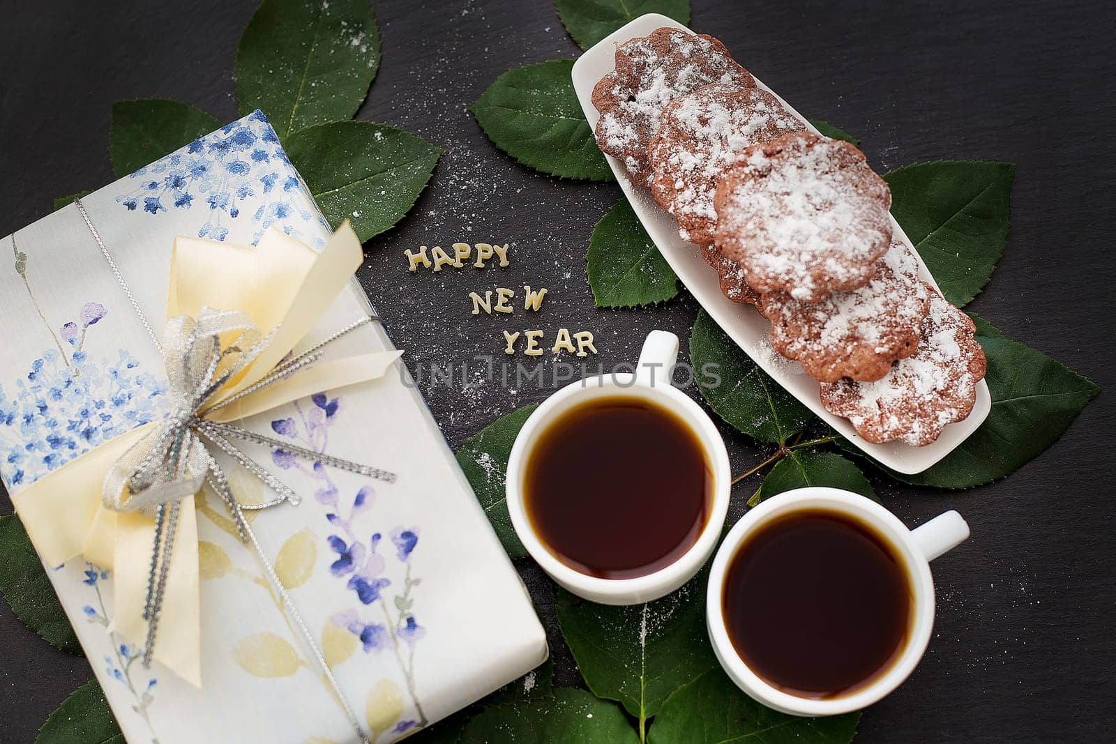 inscription of new year on a black board with a gift, muffins and coffee