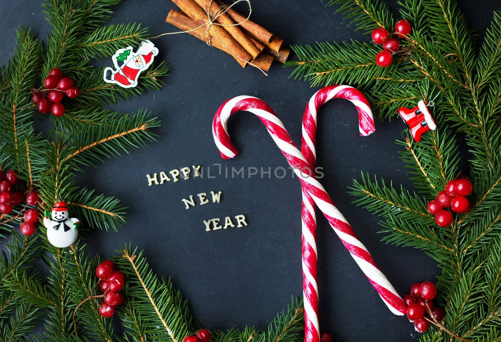 Christmas tree with ornaments and candy on a black background. The inscription Happy New Year.