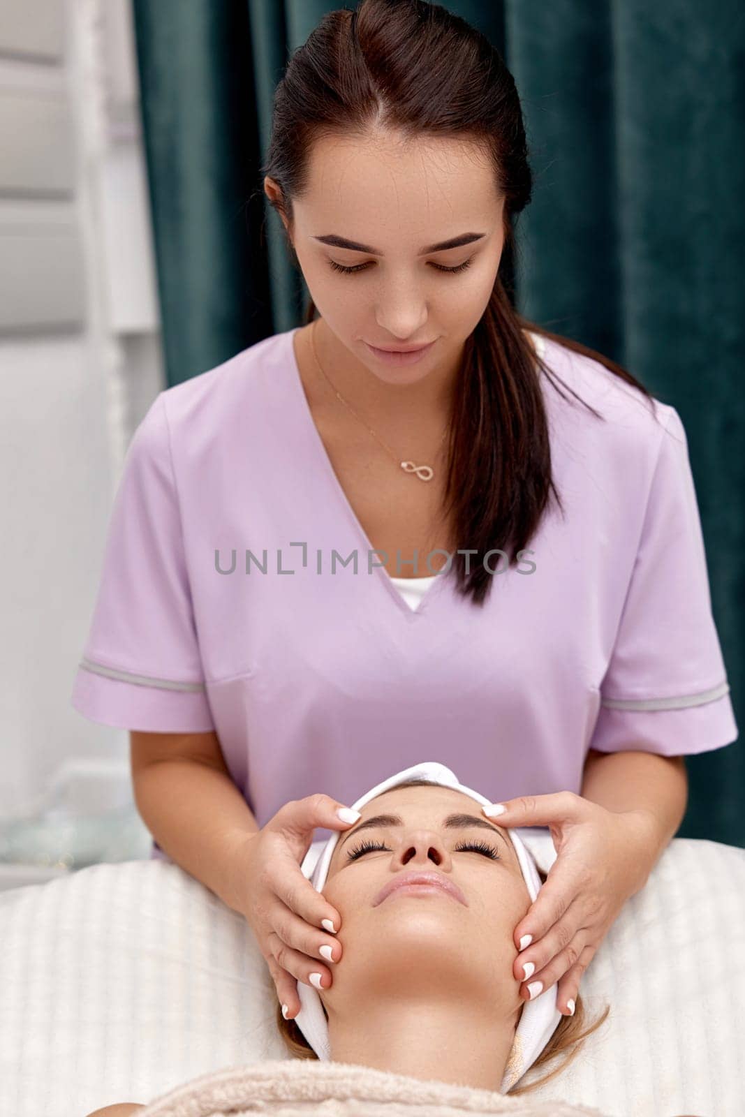 woman getting face massage treatment in beauty salon. by erstudio