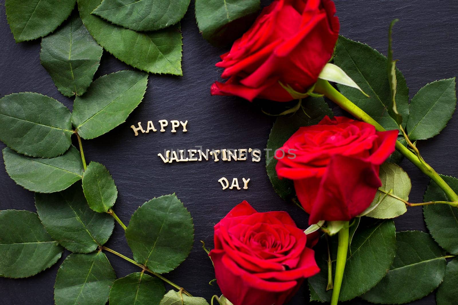 The inscription Happy Valentine on a black background with red roses