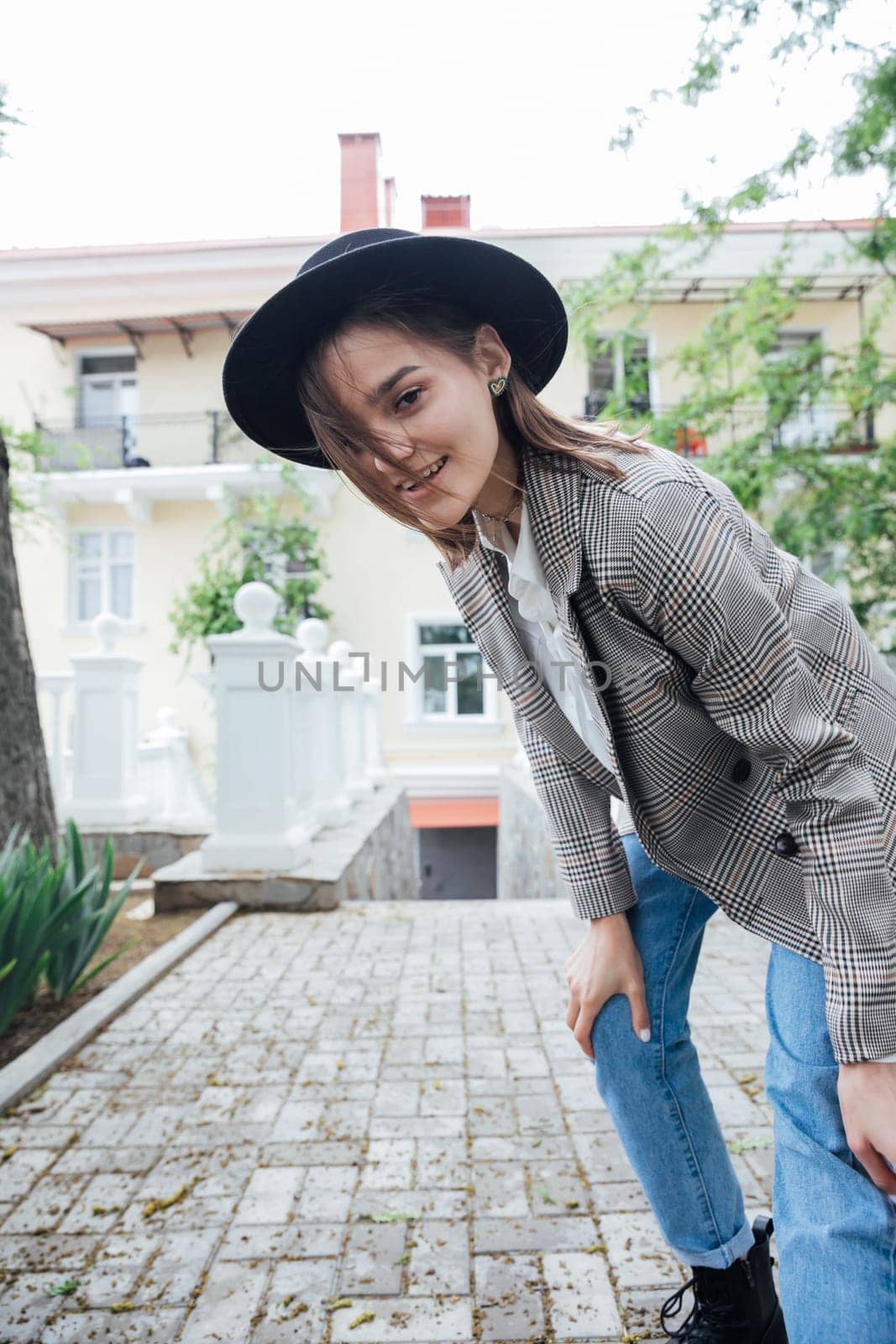 Beautiful young brunette woman in hat walking in autumn city