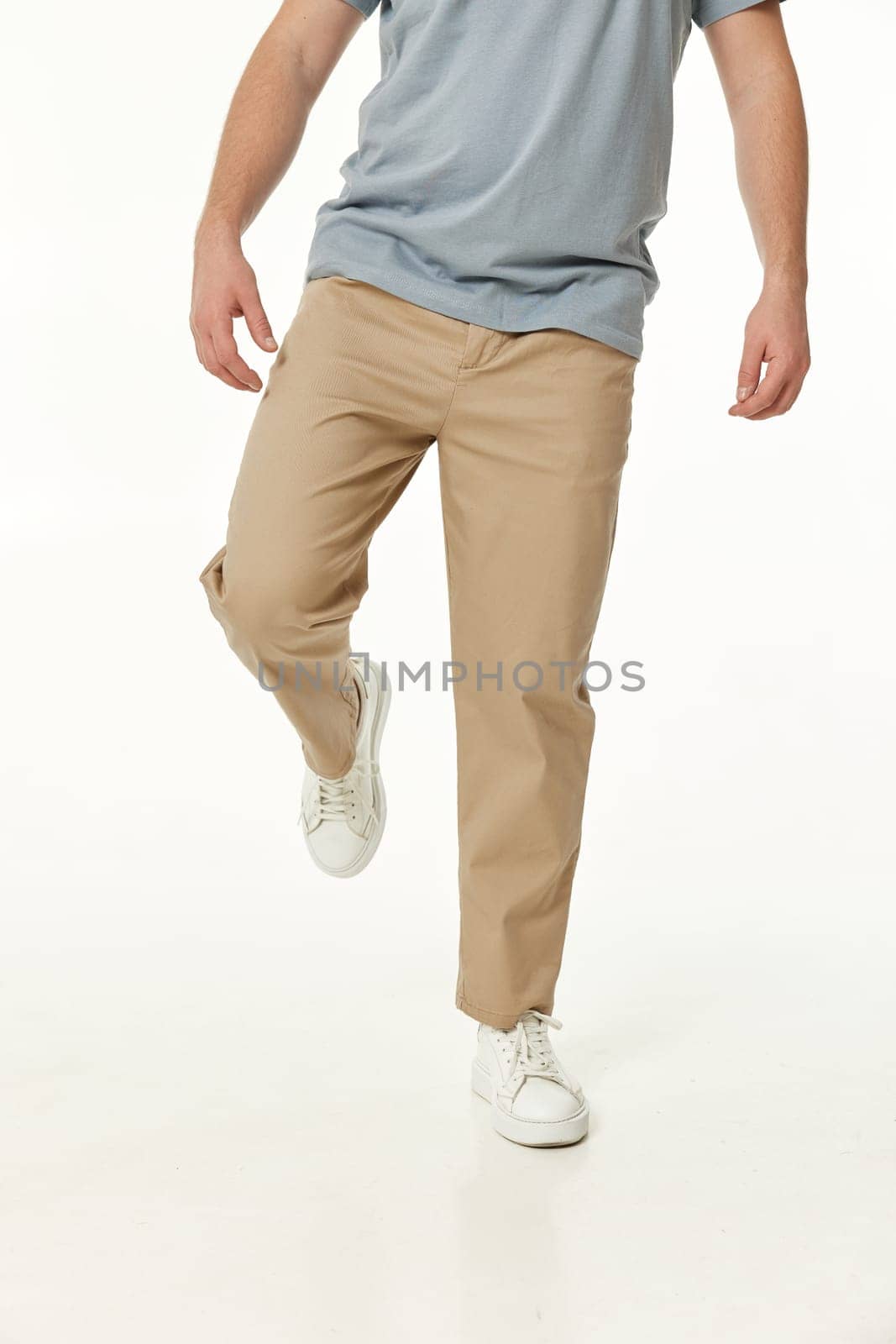 man wearing white sneakers and casual beige pants and walking on studio background