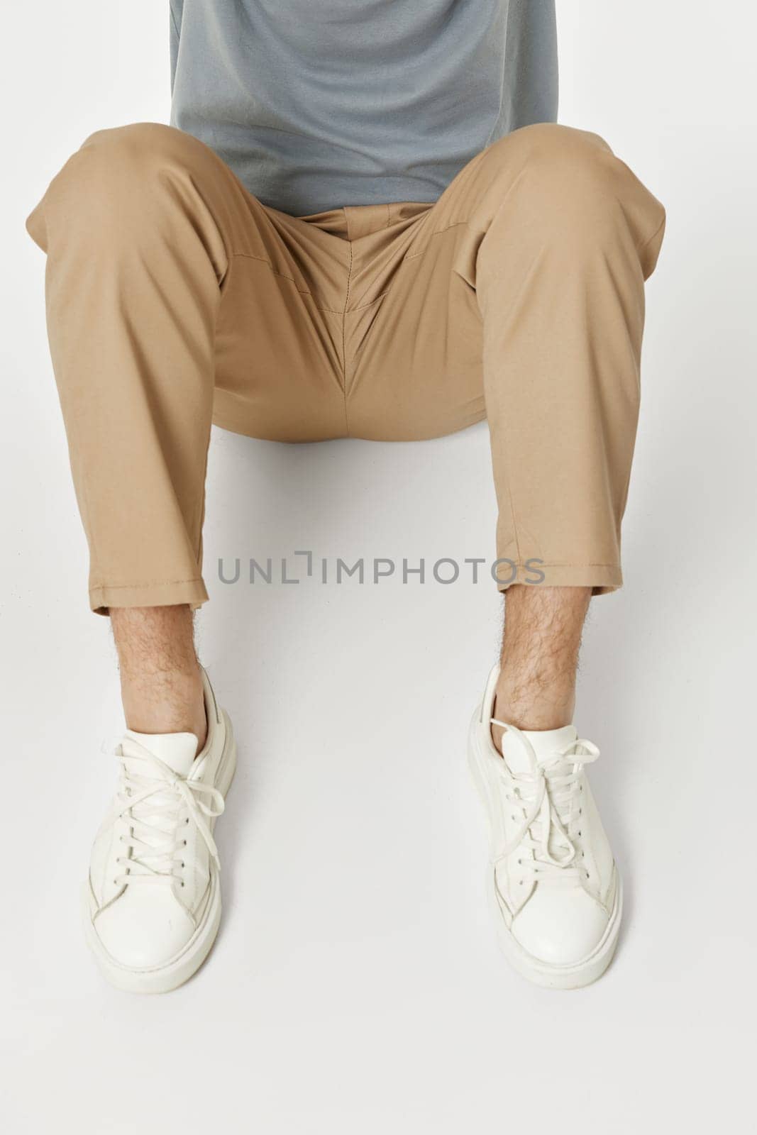 man wearing white sneakers and beige pants sitting on floor