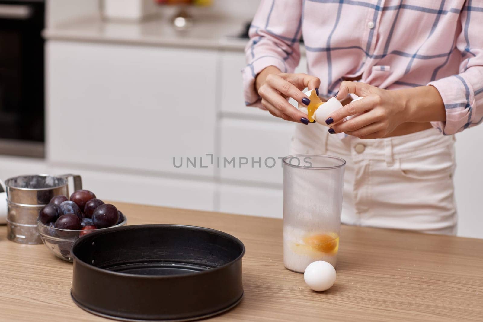 female hands breaking eggs for baking at modern kitchen