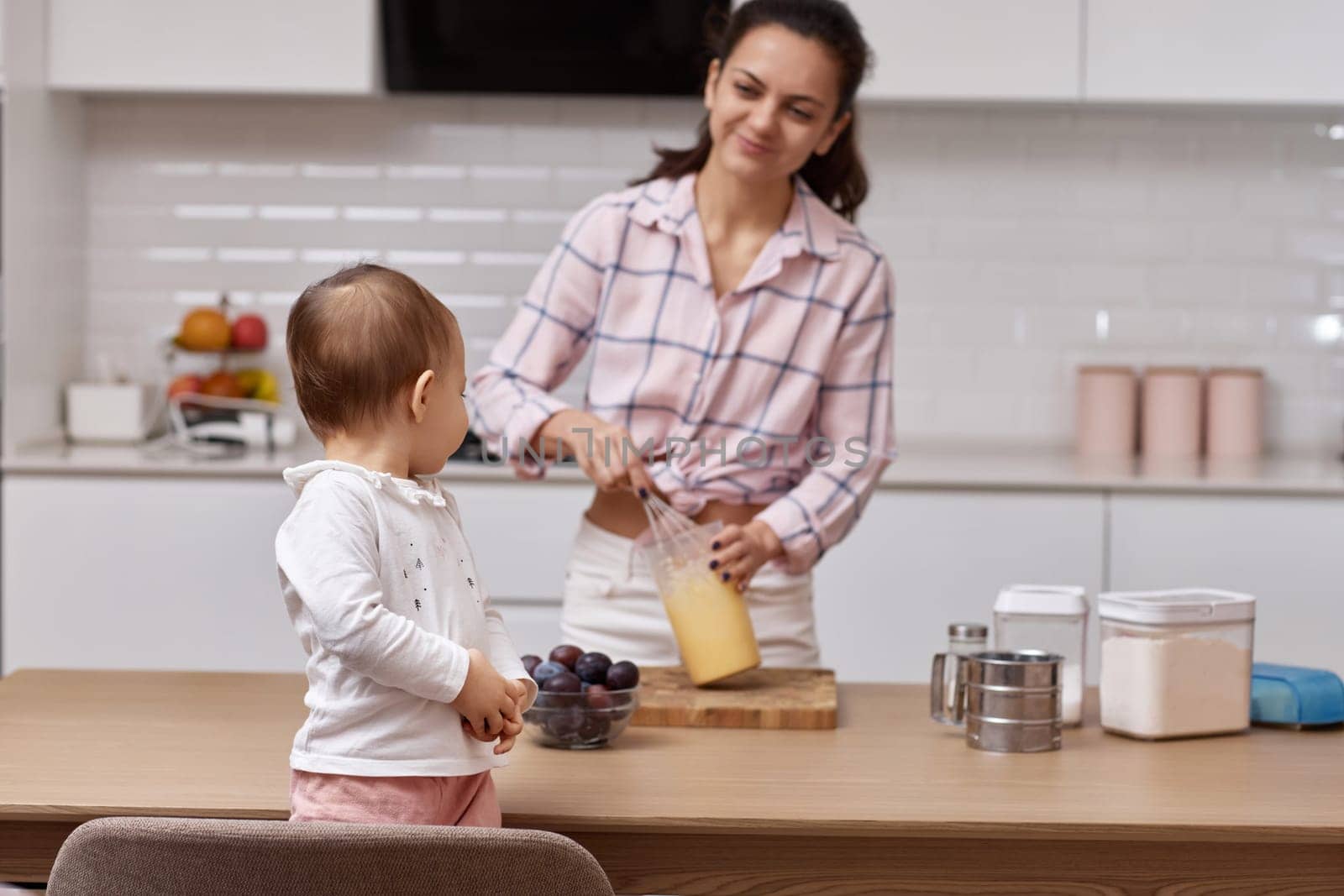 mother with her little daughter preparing the dough at kitchen. baking together