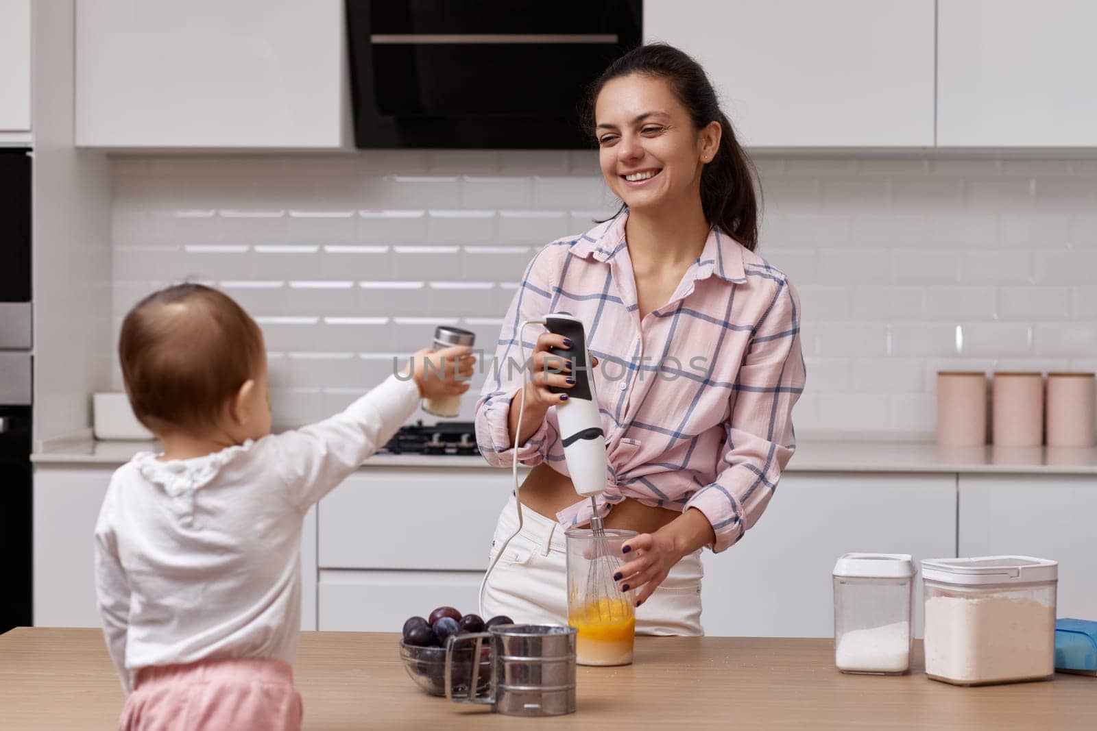 happy mother with her little daughter cooking at white kitchen. baking together