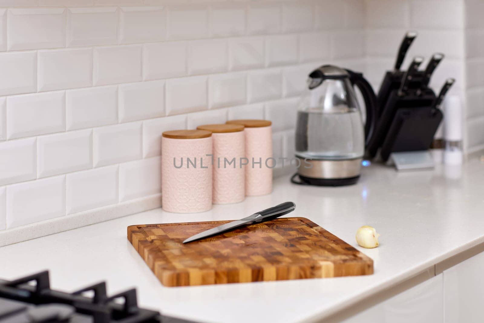 Knife and fresh piece of raw meat on wooden cutting board in modern white kitchen