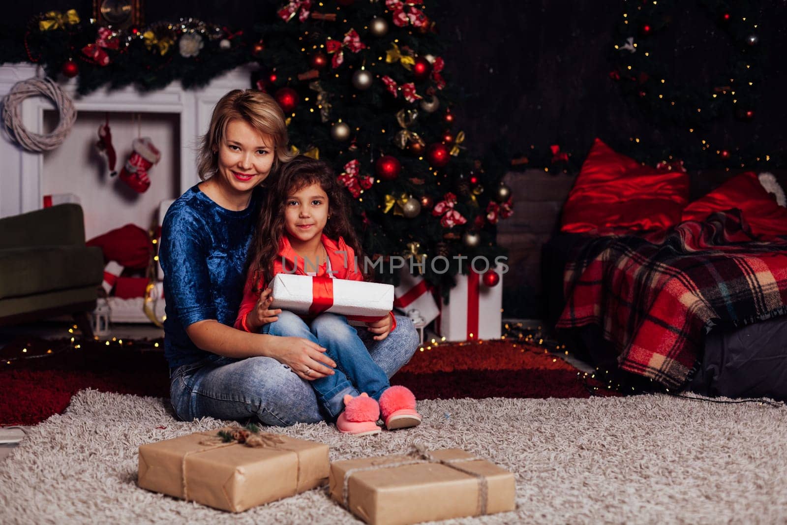 Mom and daughter at the christmas tree with gifts and toys