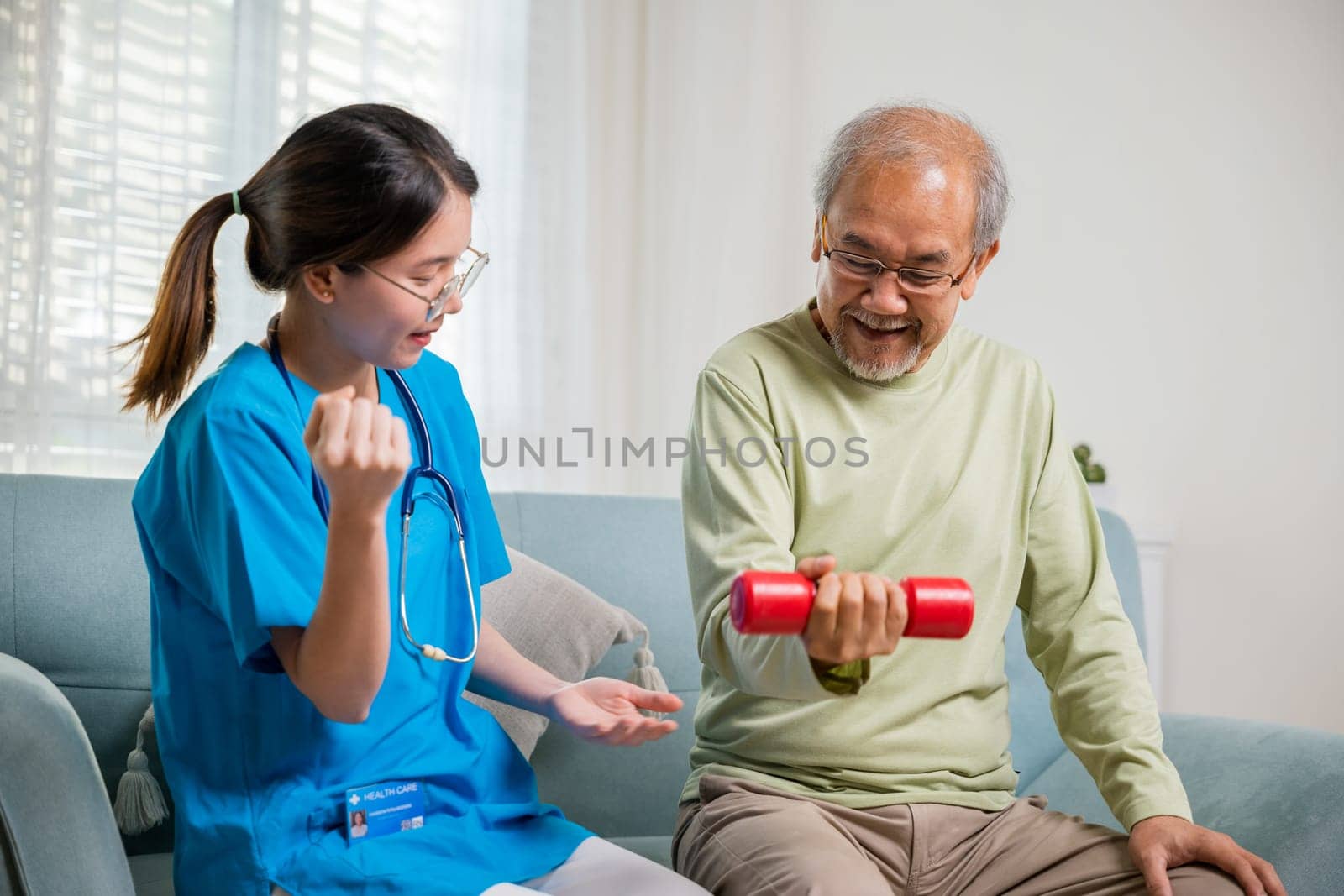 Young nurse physiotherapist helping old man in lifting dumbell at home, Asia nurse support elderly retirement sitting on sofa using red dumbbell workout exercise physical recovery, Health care concept
