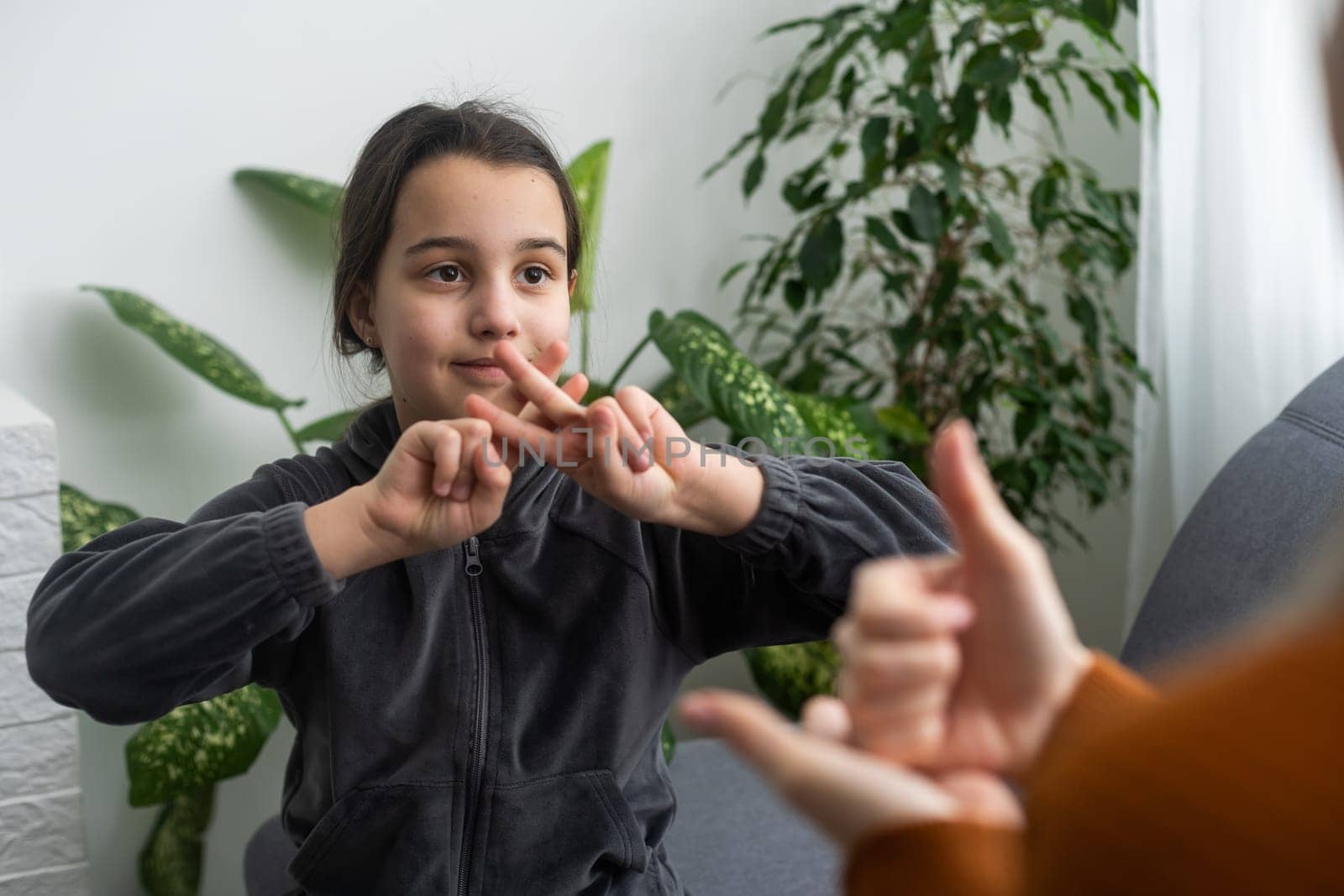 daughter talk with middle aged mother people using sign language, family sitting on armchair side view, teacher teach teenager deaf-mute girl to visual-manual gestures symbols concept image.