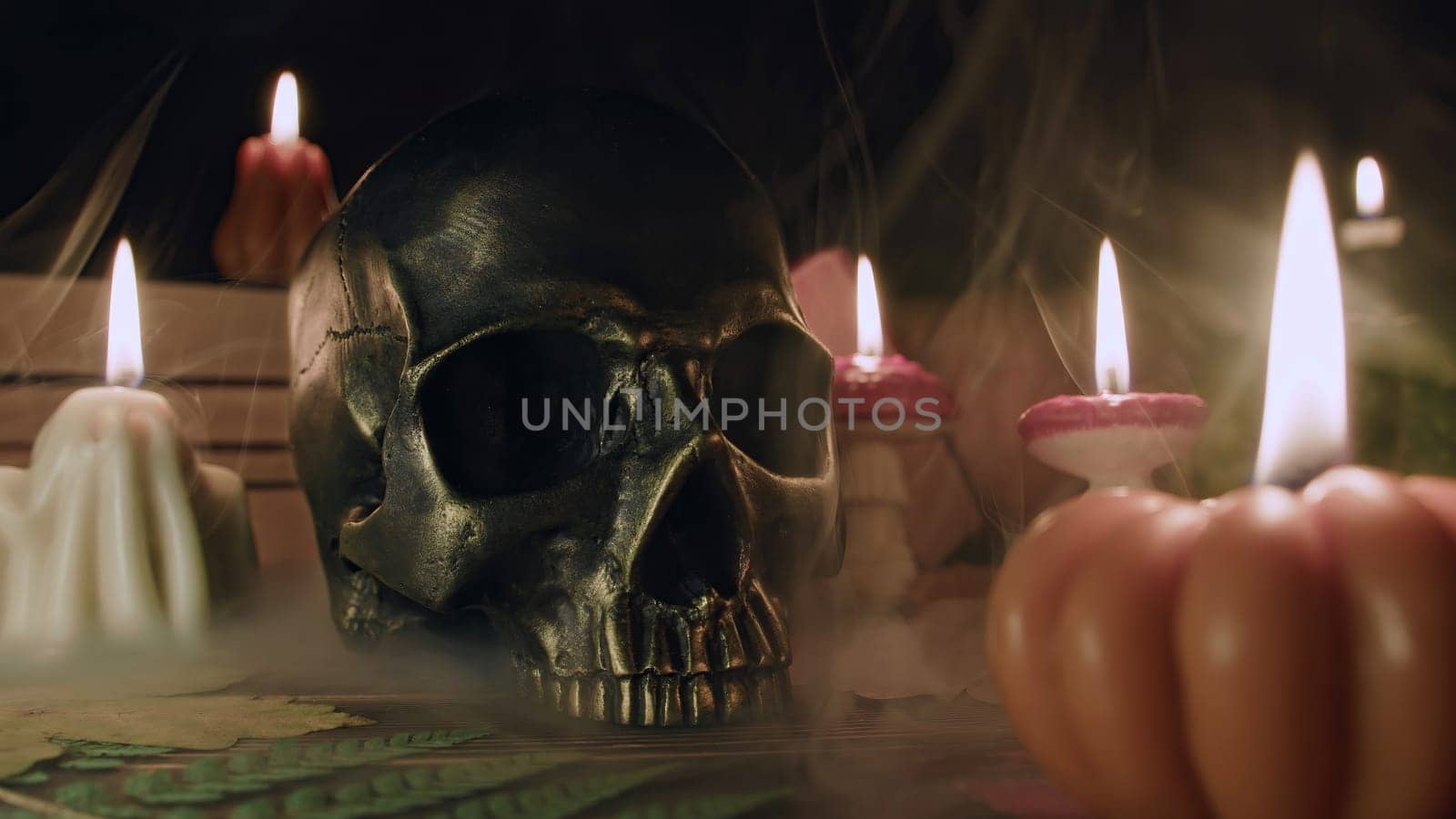 Mystique background - bronze human skull with candles. Visual gothic aesthetic. Autumn pumpkin candle, falling leaves. Ambience of fall. Seasonal promotions or dramatic visual storytelling.