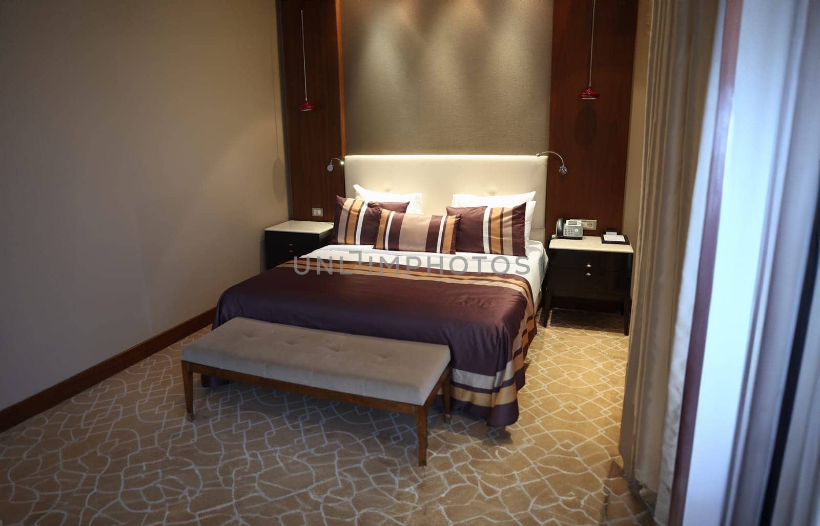 Bed with brown pillows and bedspread in hotel room. Interior design concept