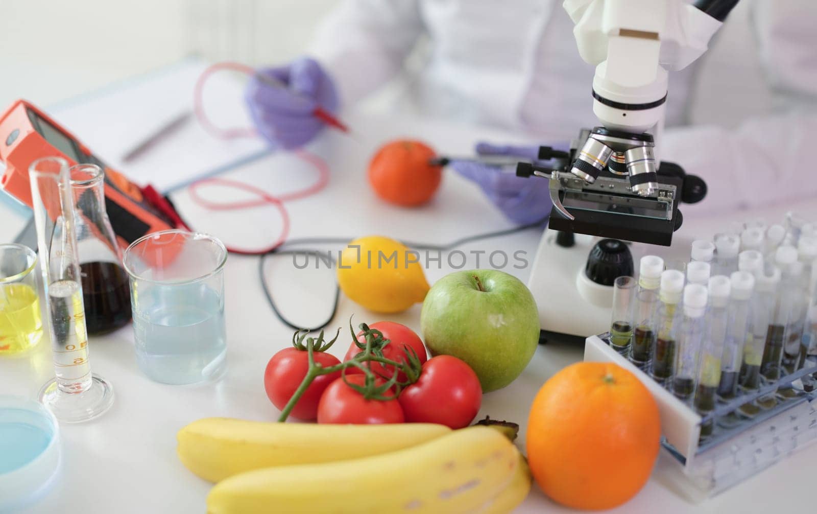 Scientist chemist studying amount of toxic substances in vegetables and fruits in chemical laboratory. Food quality control nitrate content concept