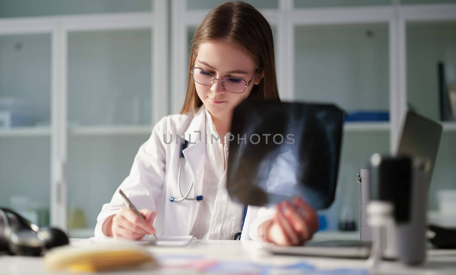 Therapist doctor holding xray of lungs in hands and writing in medical documents in clinic. Diagnosis and treatment of pneumonia and lung cancer concept