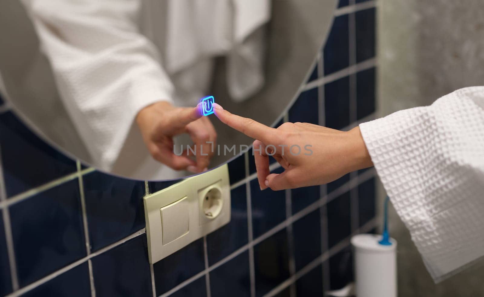 Woman hand pressing button for turning on light and heating mirror in bathroom closeup. Modern home accessories concept