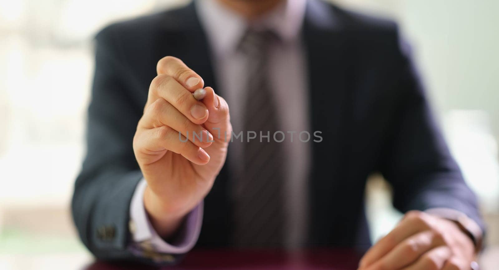Businessman holding ballpoint pen in front of camera at work in office closeup. Signing contract for employment concept