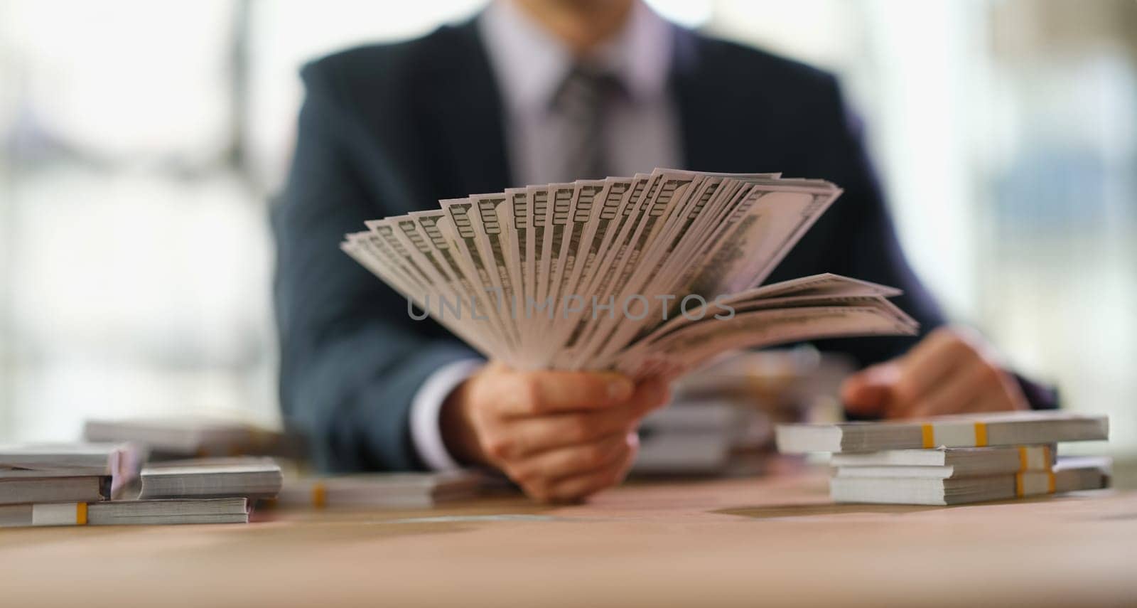 Businessman banker holding fan of dollar bills in hand closeup by kuprevich