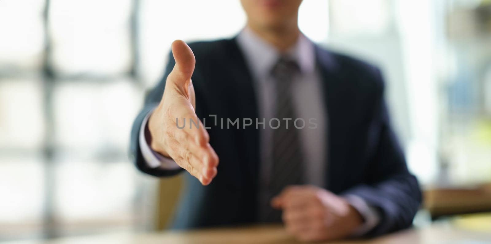 Businessman in suit extending his hand for handshake to partner at work in office closeup. Successful customer service concept
