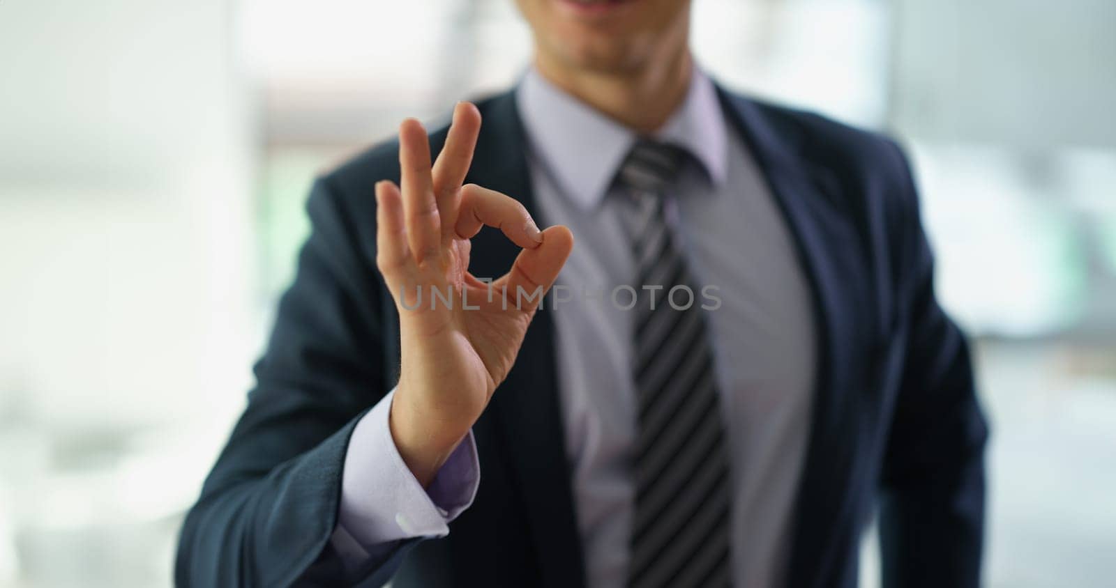 Businessman in suit showing hand gesture ok at work in office closeup by kuprevich