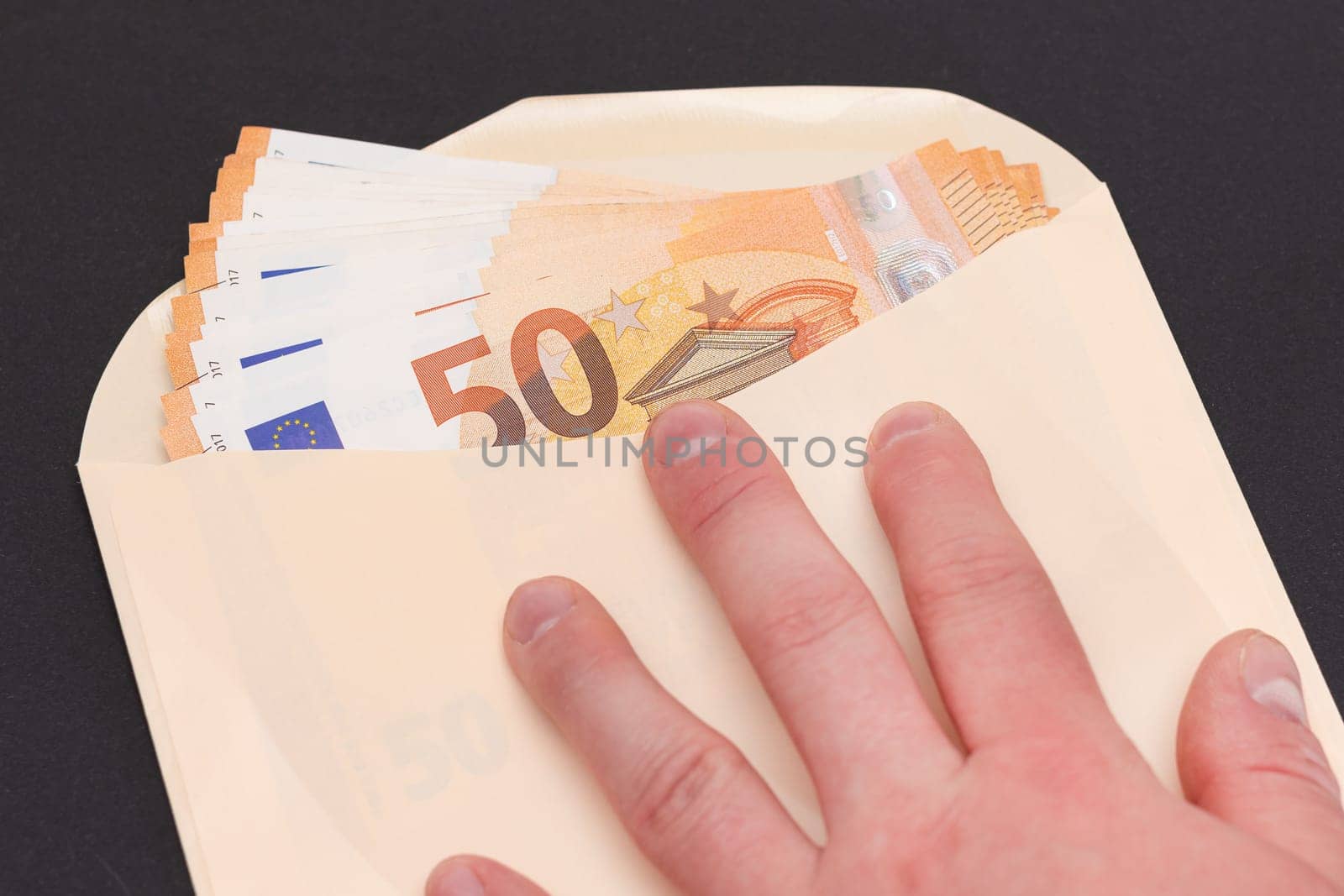 Hand Holds An Orange Paper Envelope with Stack of 50-Euro Banknotes Inside by InfinitumProdux