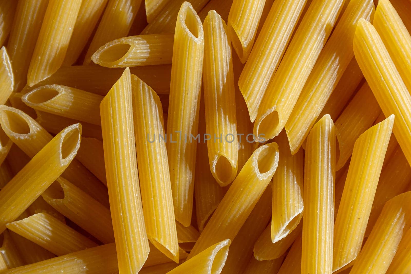 Uncooked Penne Rigate Pasta Background by InfinitumProdux