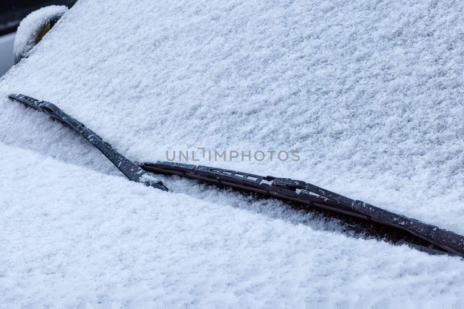 snow covered car windshield, wipers and bonnet - closeup full-frame view under daylight