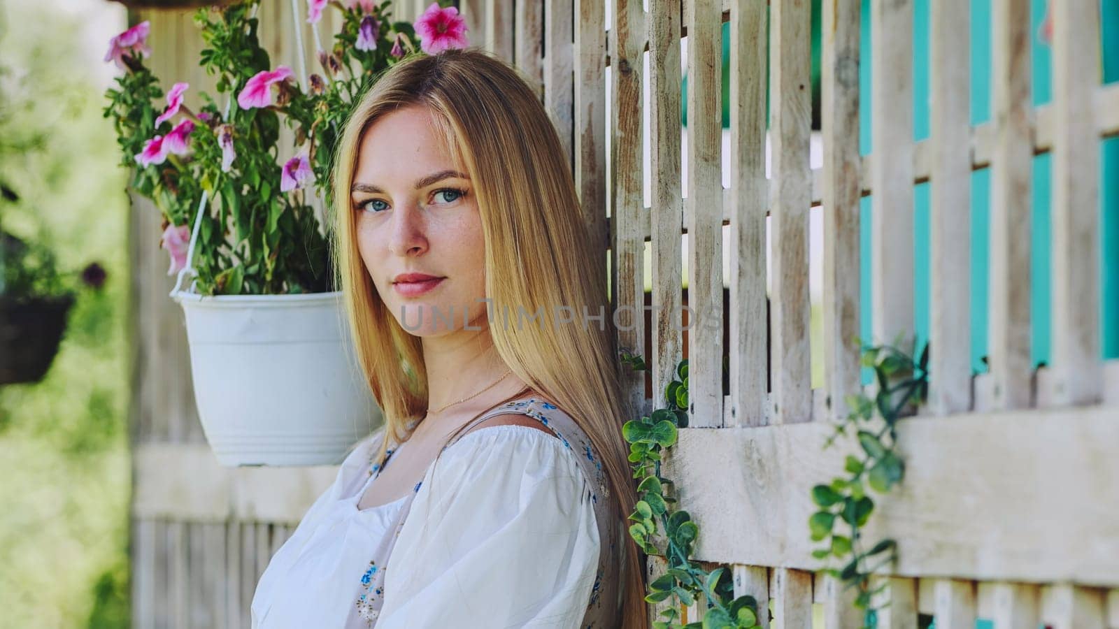 A girl of Slavic appearance poses at home with flowers