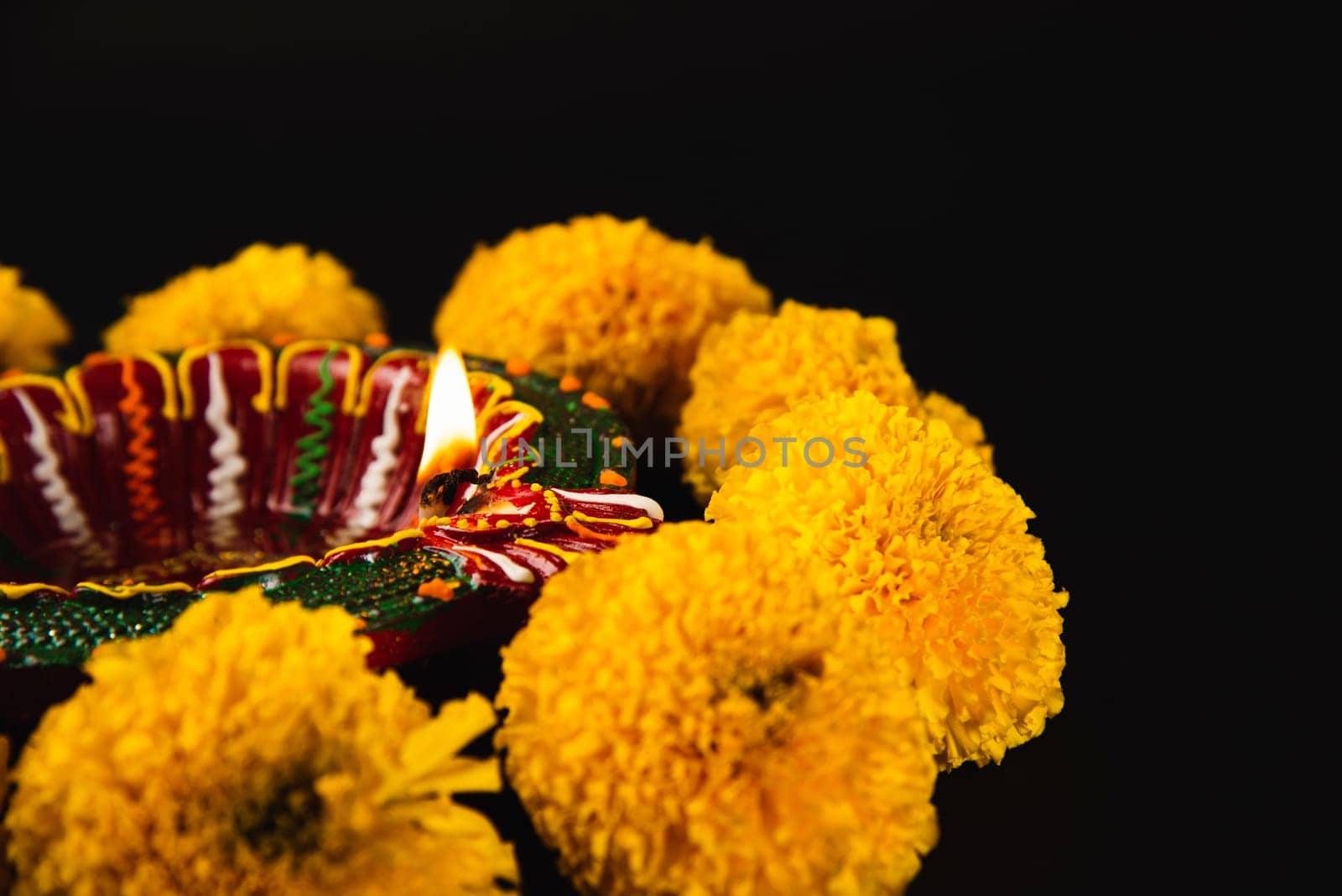 Intricate Diwali lamp and colorful flower rangoli illuminate a captivating black background. Ideal for Diwali, weddings, and cultural celebrations.