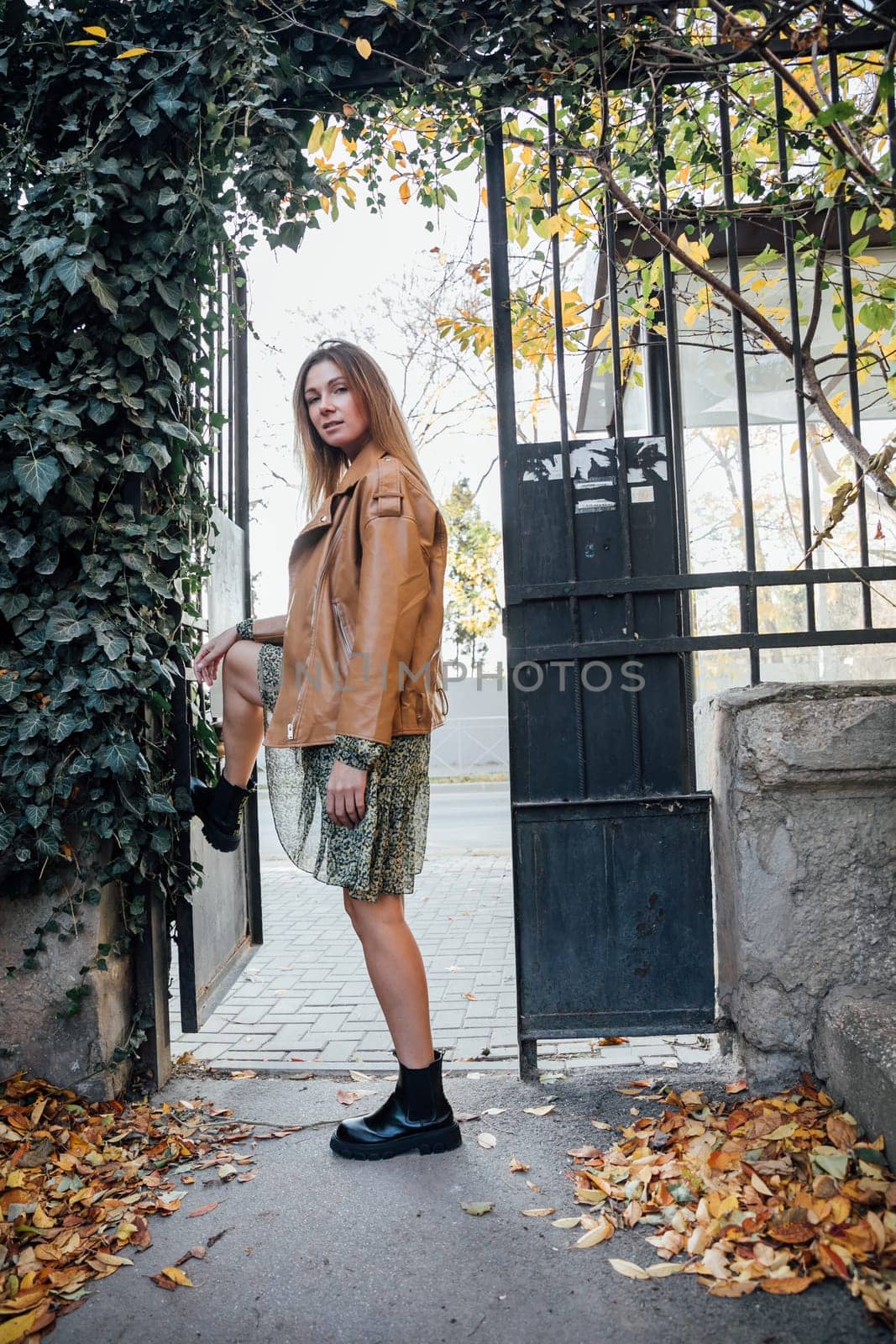 Beautiful woman walking in autumn city with fallen leaves by Simakov