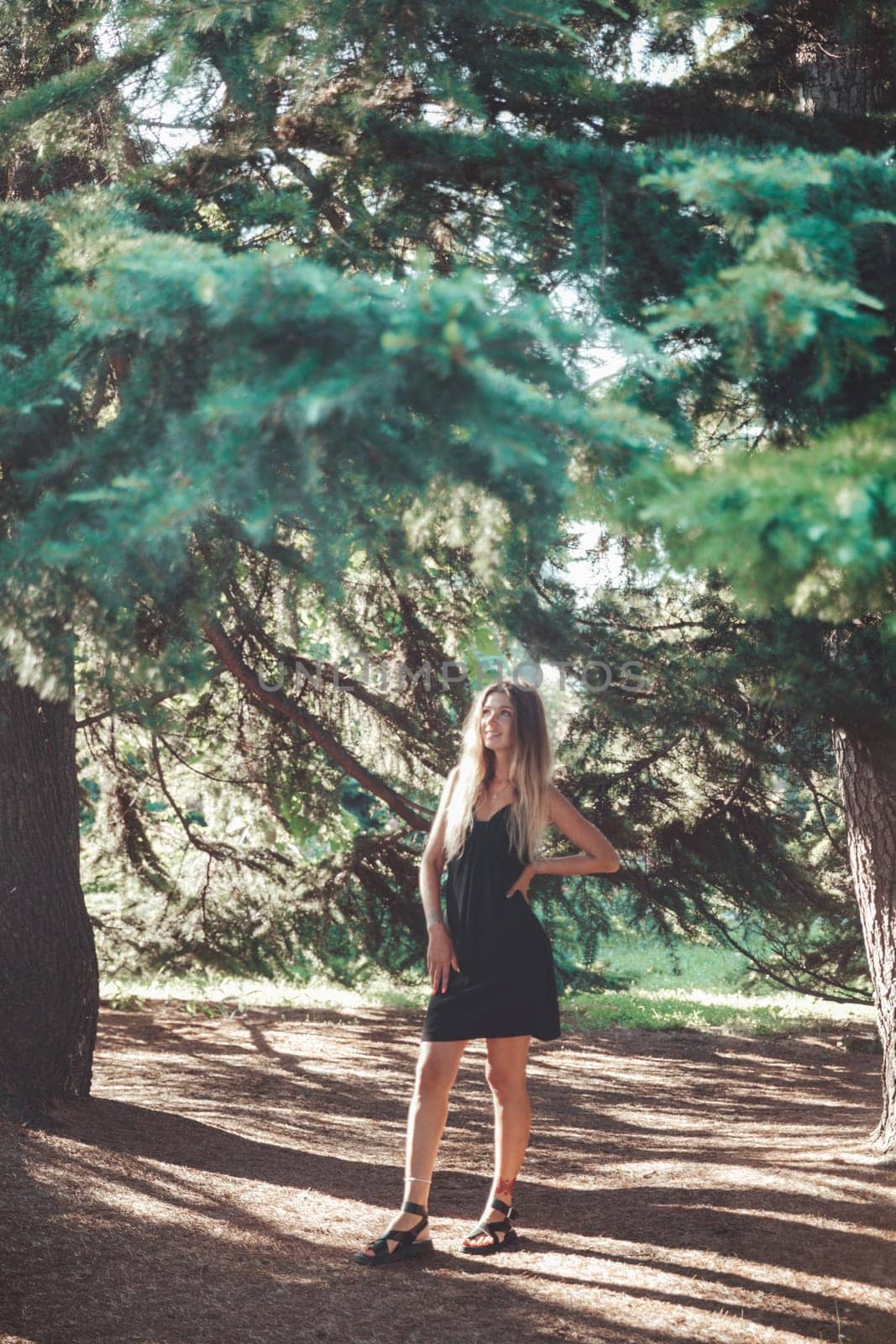 slender fashionable woman in black summer dress walking on the streets of the city